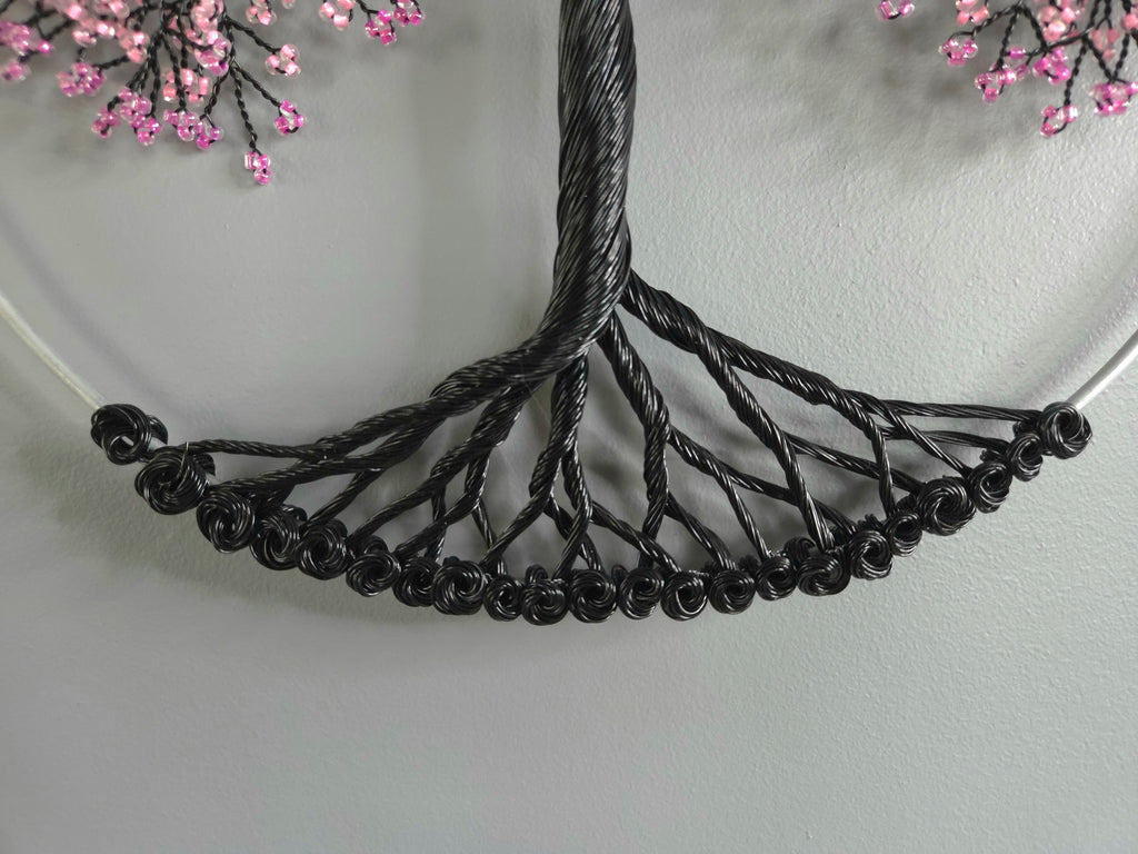 Black wire necklace on a white plate with pink flowers