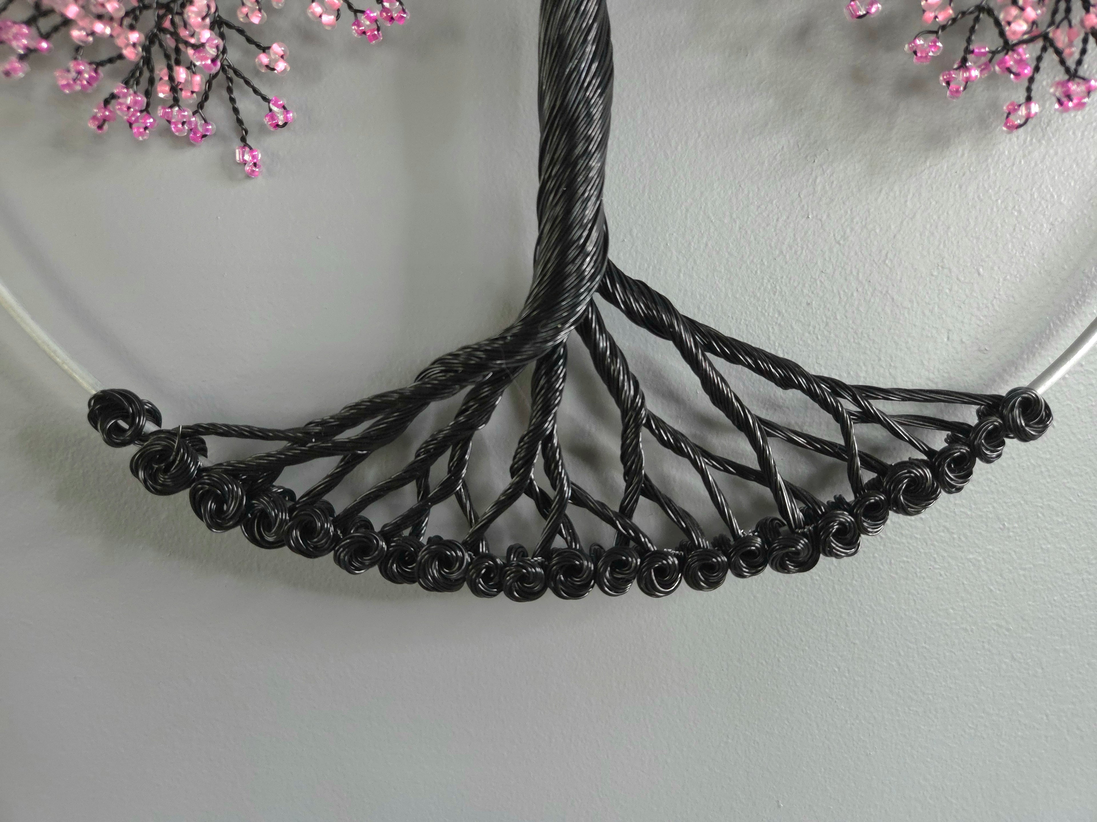 Black wire necklace on a white plate with pink flowers