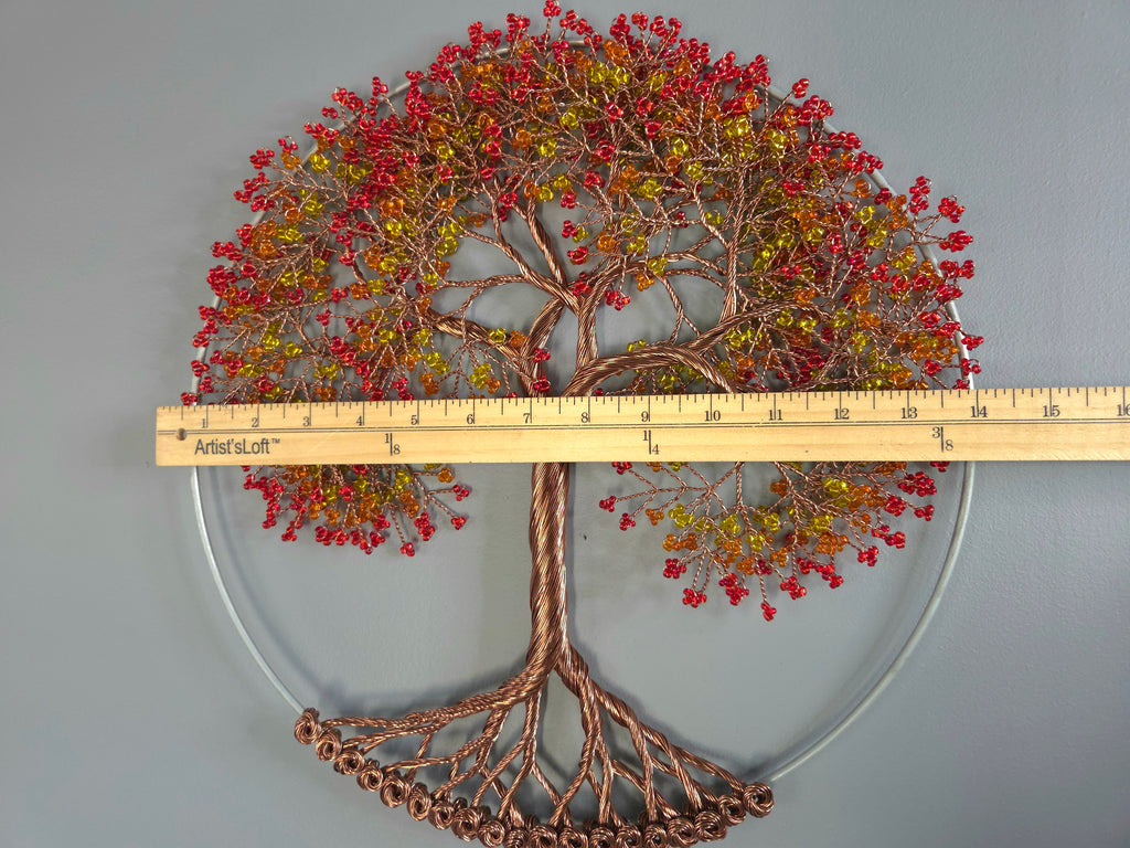 Decorative wall art of a tree with red and gold leaves, measured against a ruler.