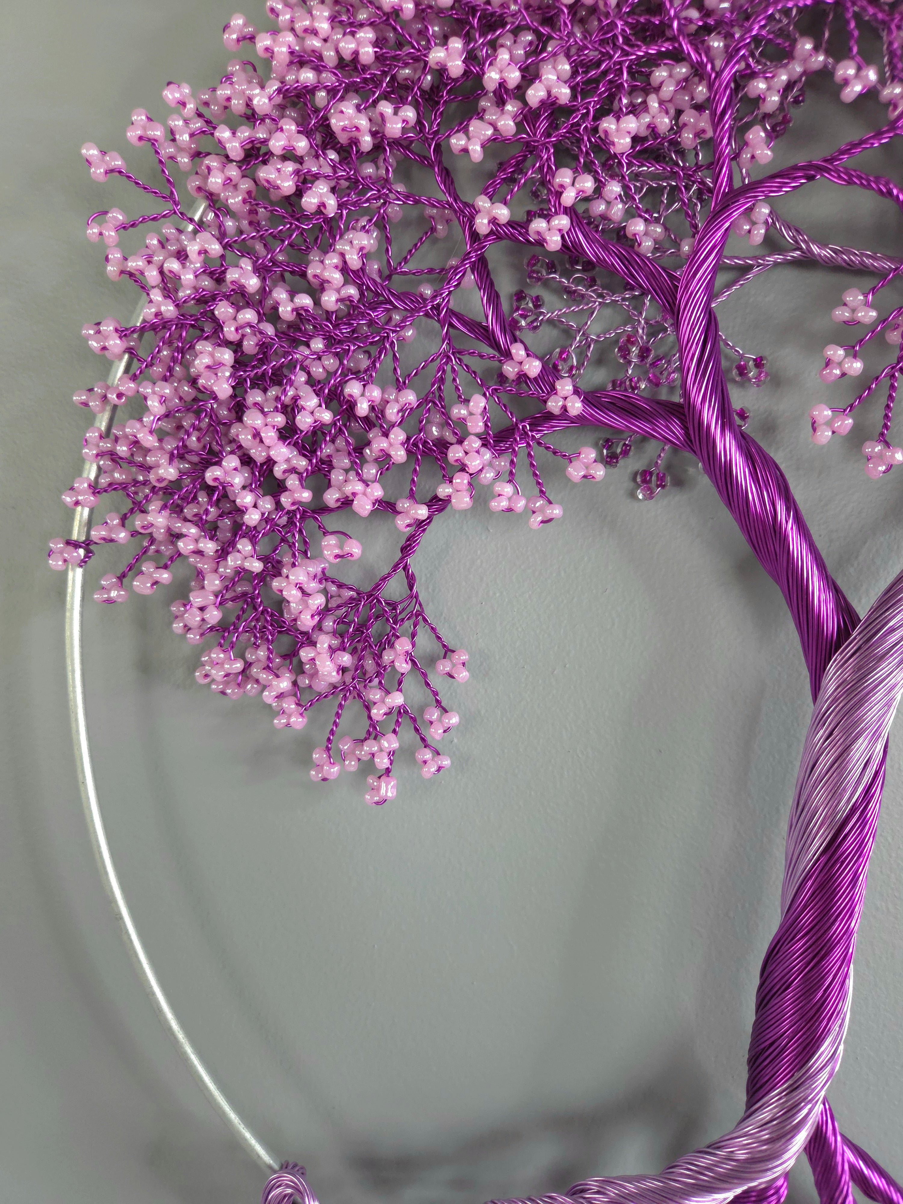 Purple decorative tree with pink beads on a gray background