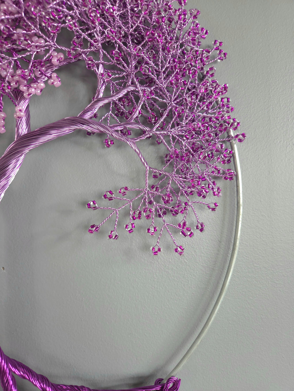 Decorative wreath with purple branches and beads on a gray background