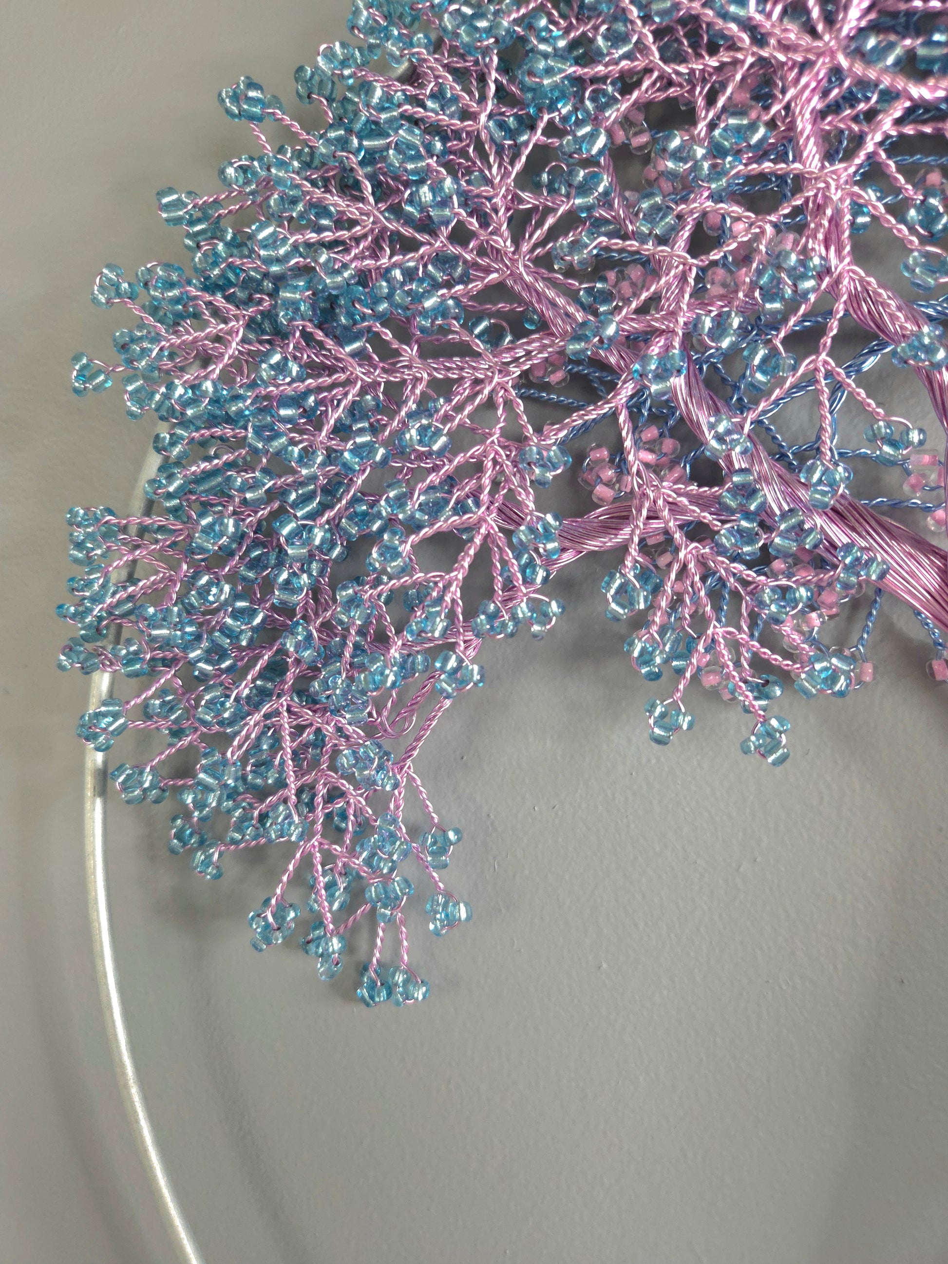 Decorative branch with pink and blue beads on a neutral background