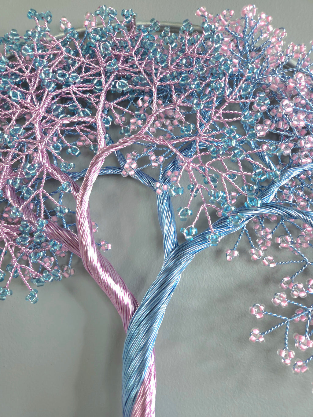Decorative tree made of pink and blue beaded branches on a gray background