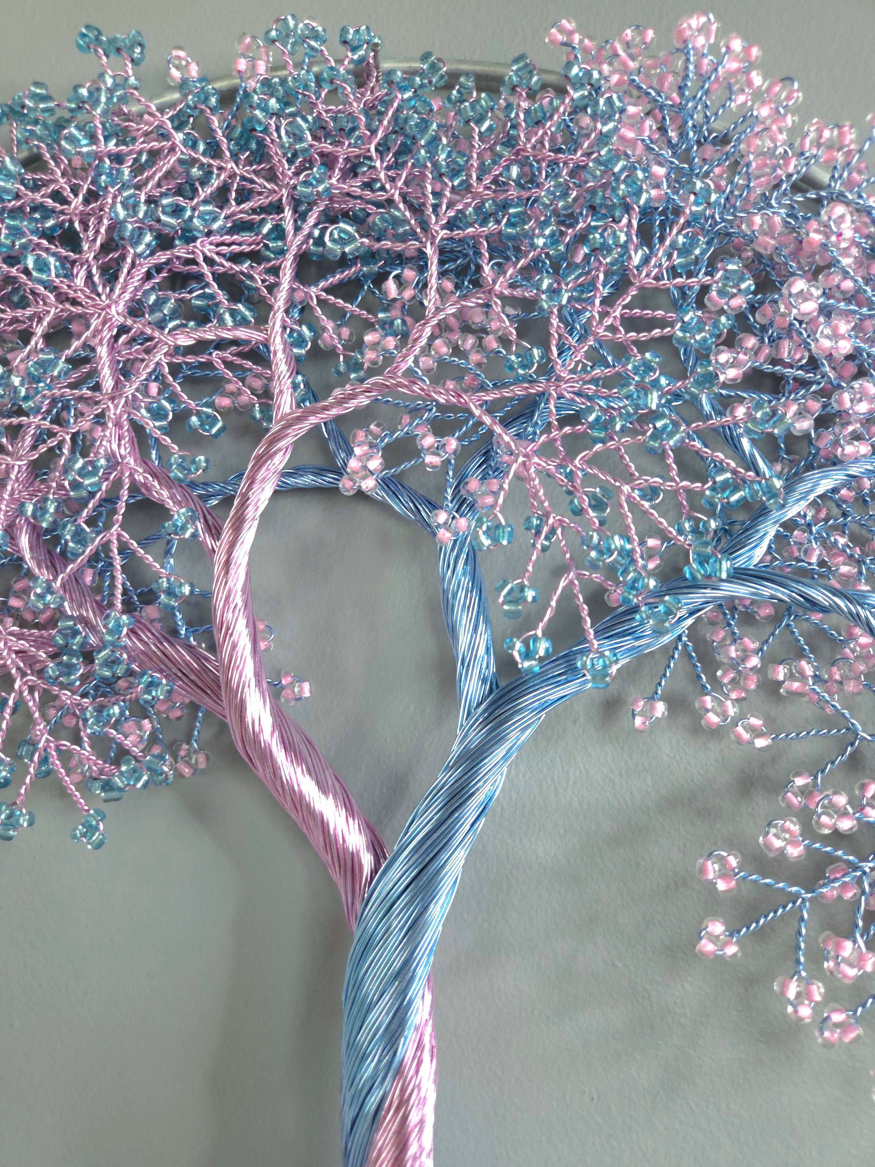 Decorative tree made of pink and blue beaded branches on a gray background
