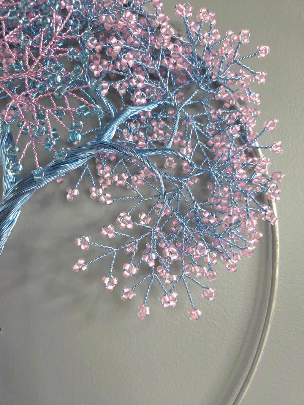 Decorative headband with blue and pink beaded branches on a plain background