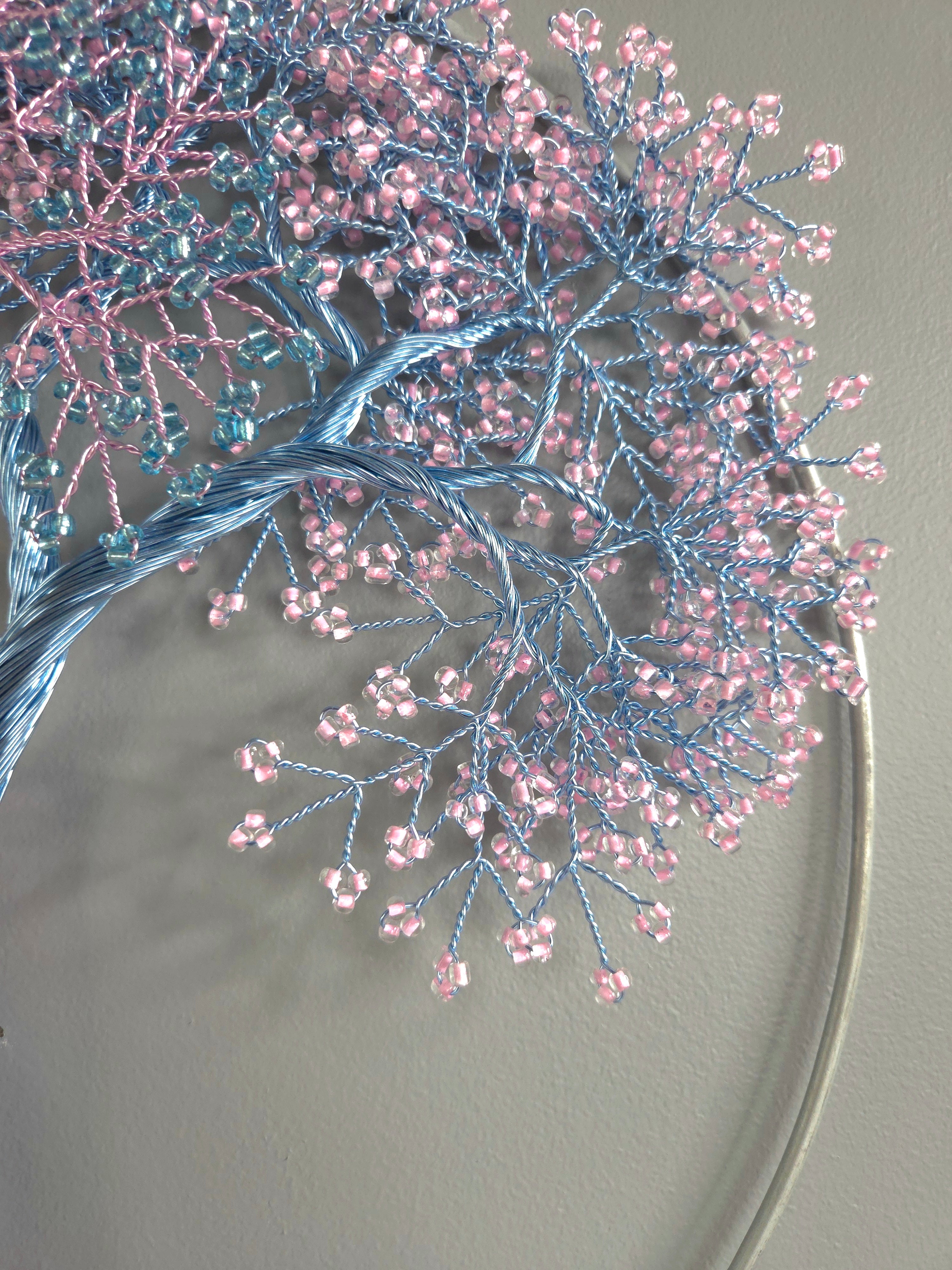 Decorative headband with blue and pink beaded branches on a plain background