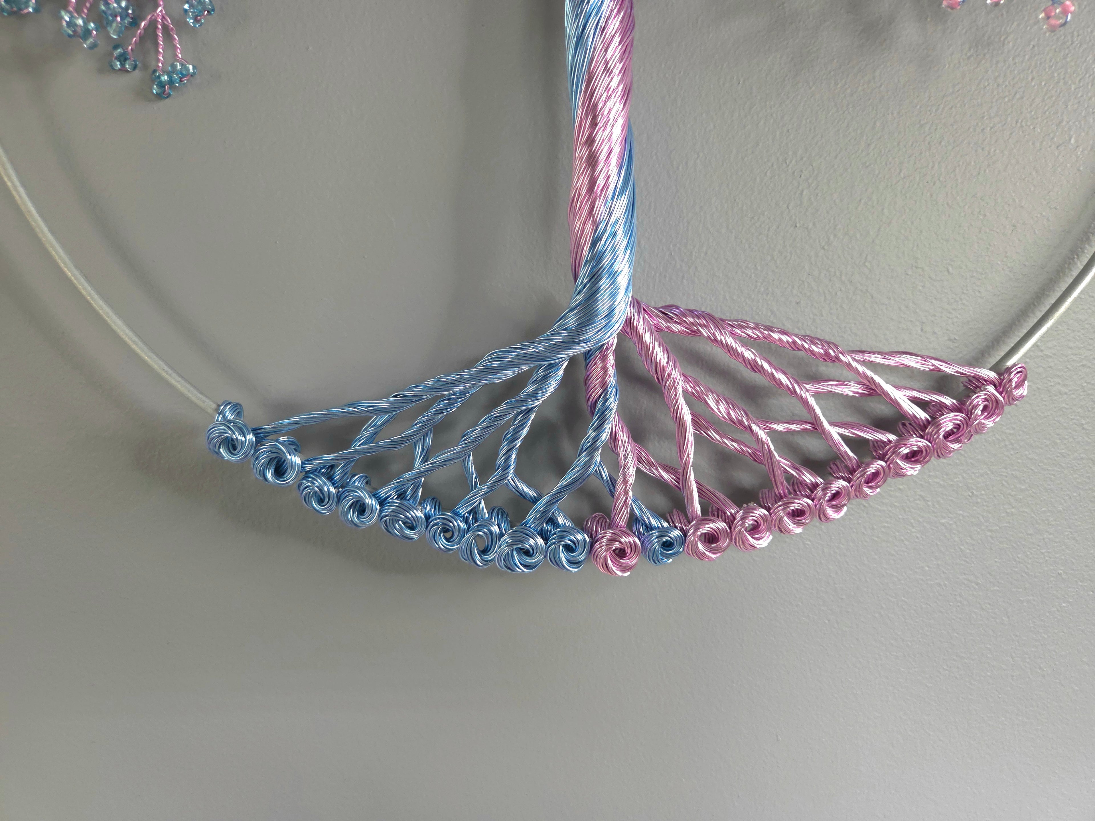 Close-up of a necklace with blue and pink beaded strands on a neutral background