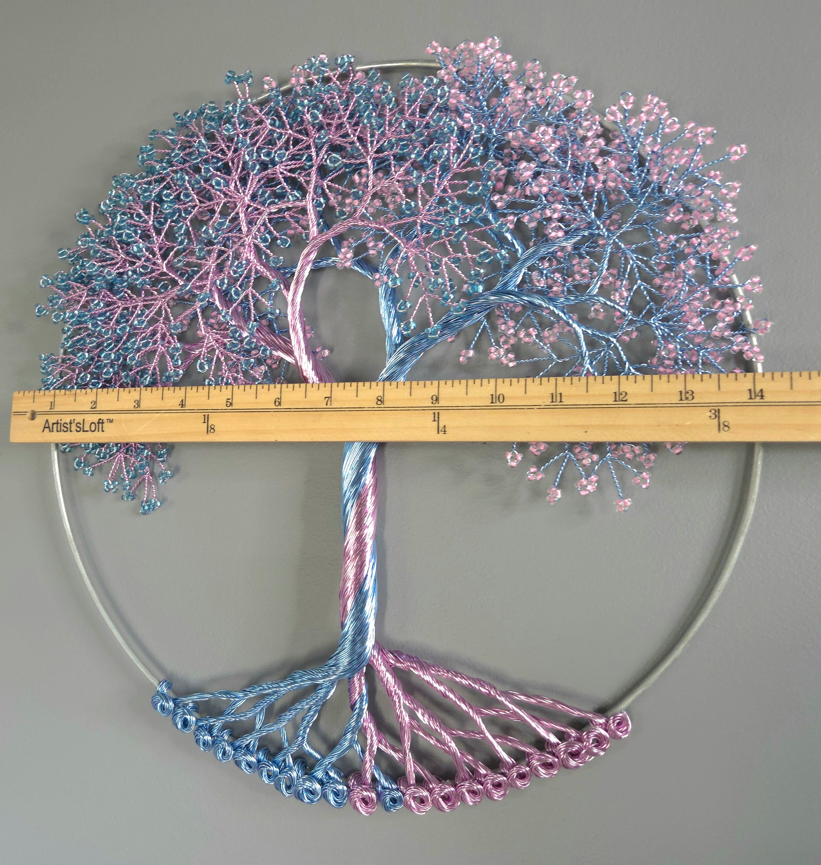 Decorative tree sculpture with pink and blue branches on a gray background, measured by a ruler.
