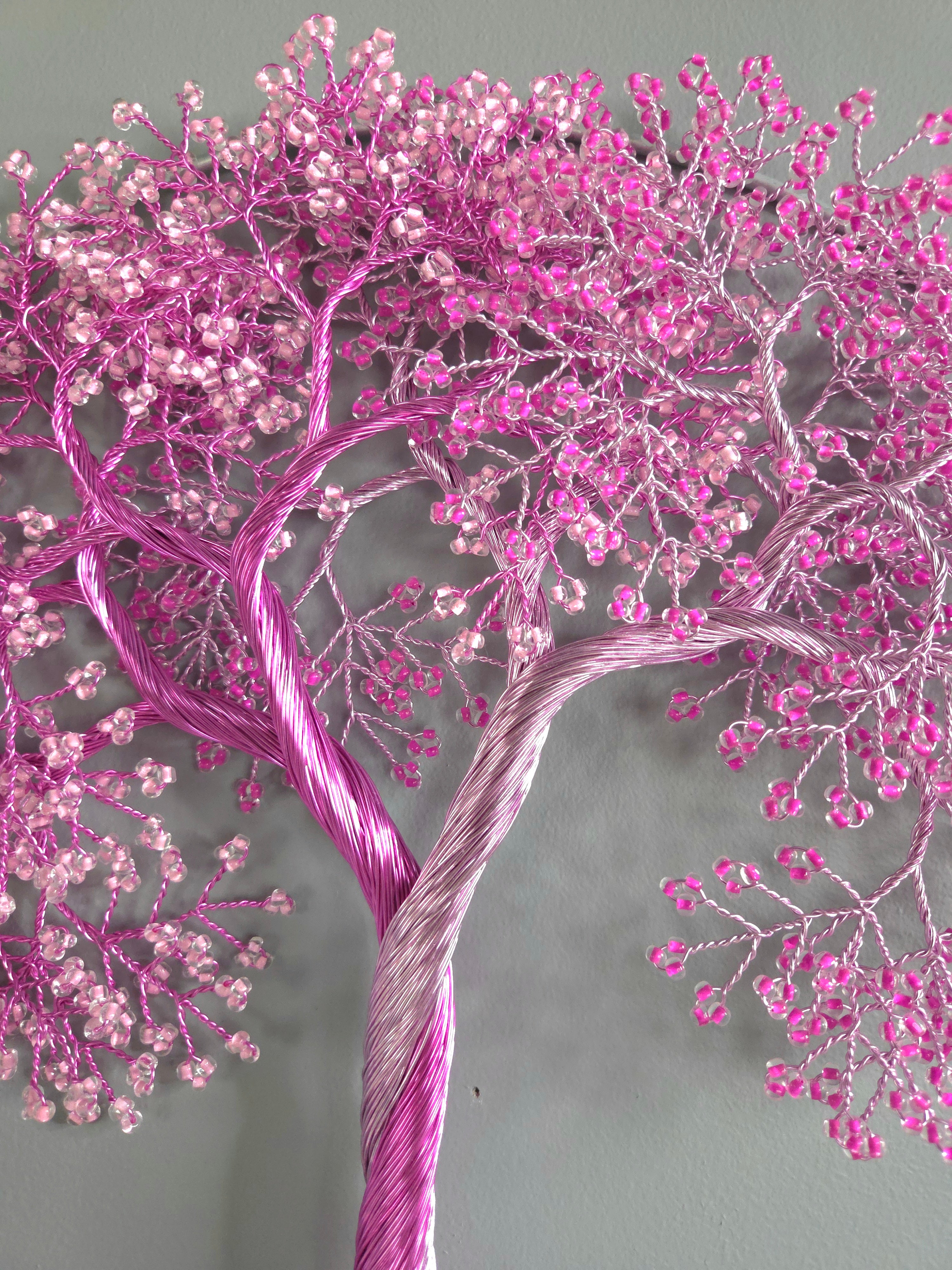 Decorative wall art of a tree with pink blossoms on a gray background