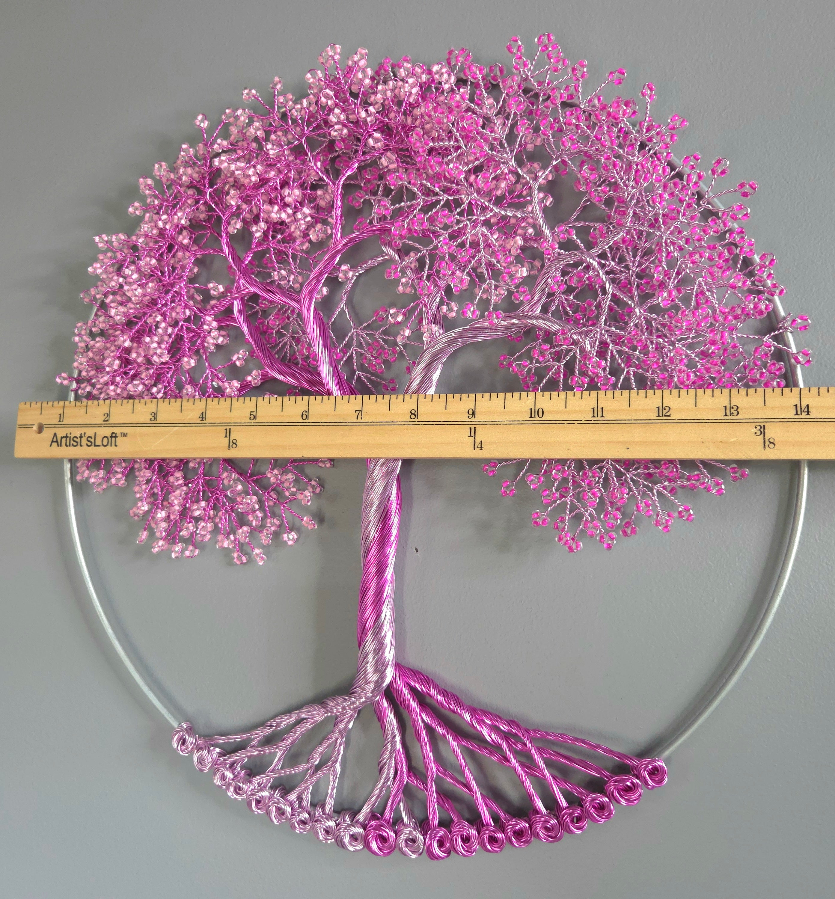 Decorative wall art of a tree with pink blossoms on a gray background