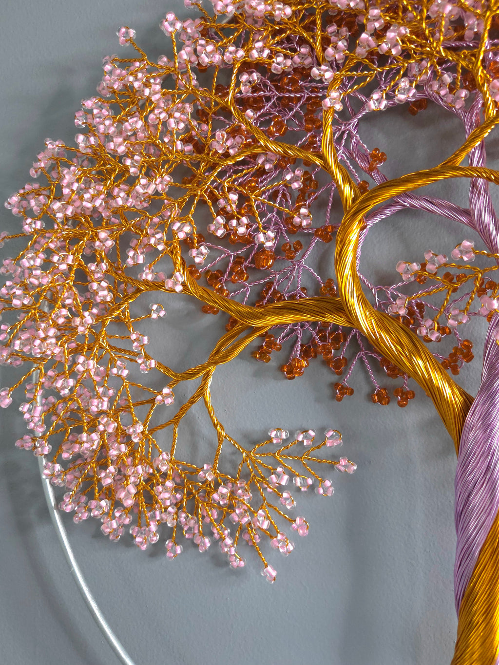 Decorative tree wall art with gold and pink branches on a light blue background