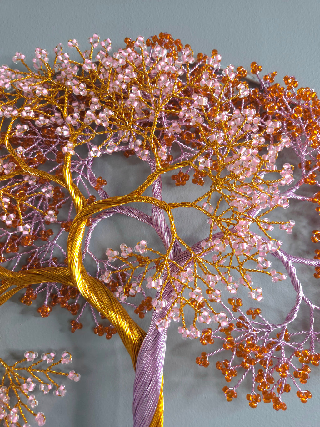 Close-up of a tree with pink and orange beads on a gray background