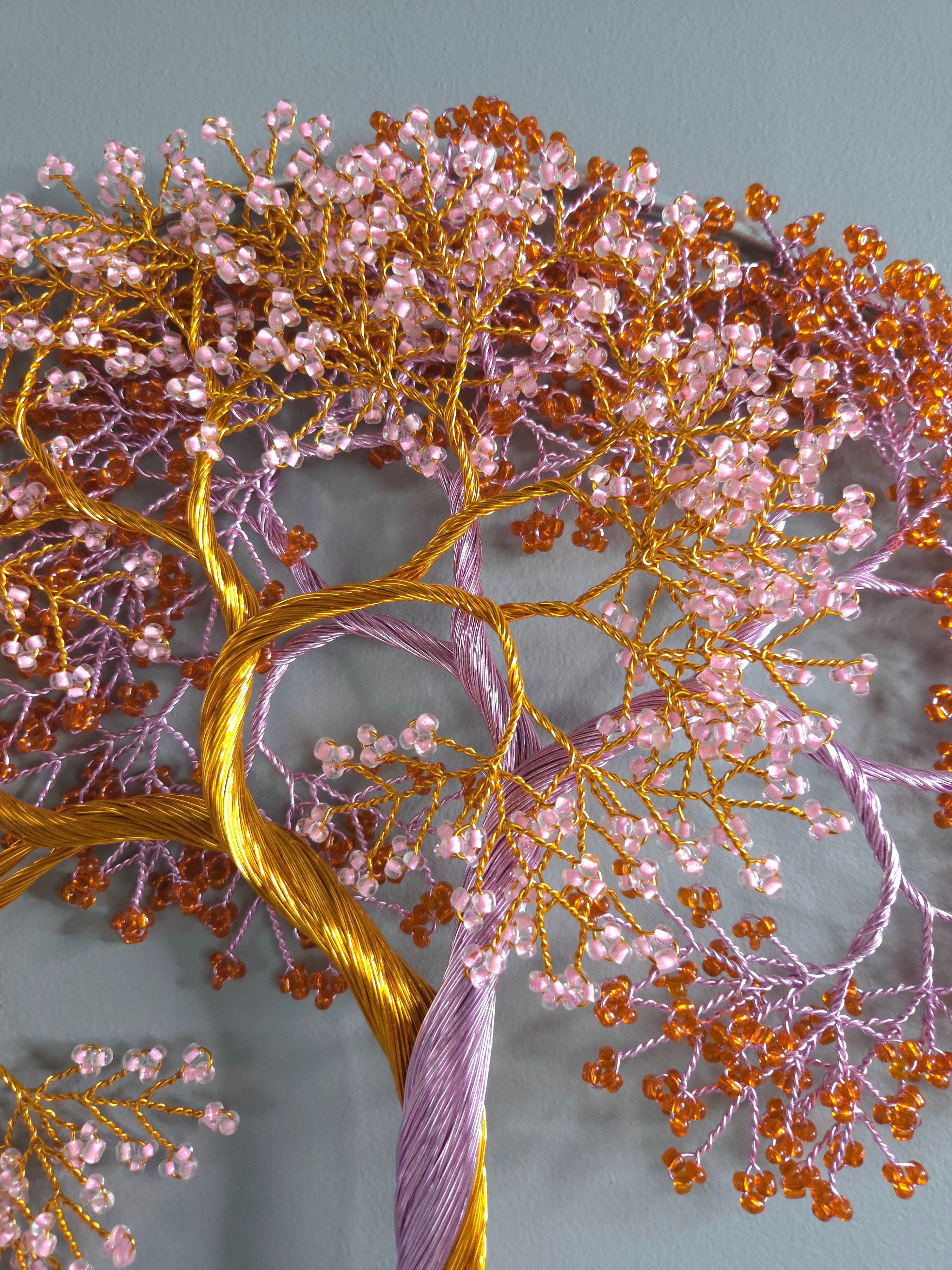 Close-up of a tree with pink and orange beads on a gray background
