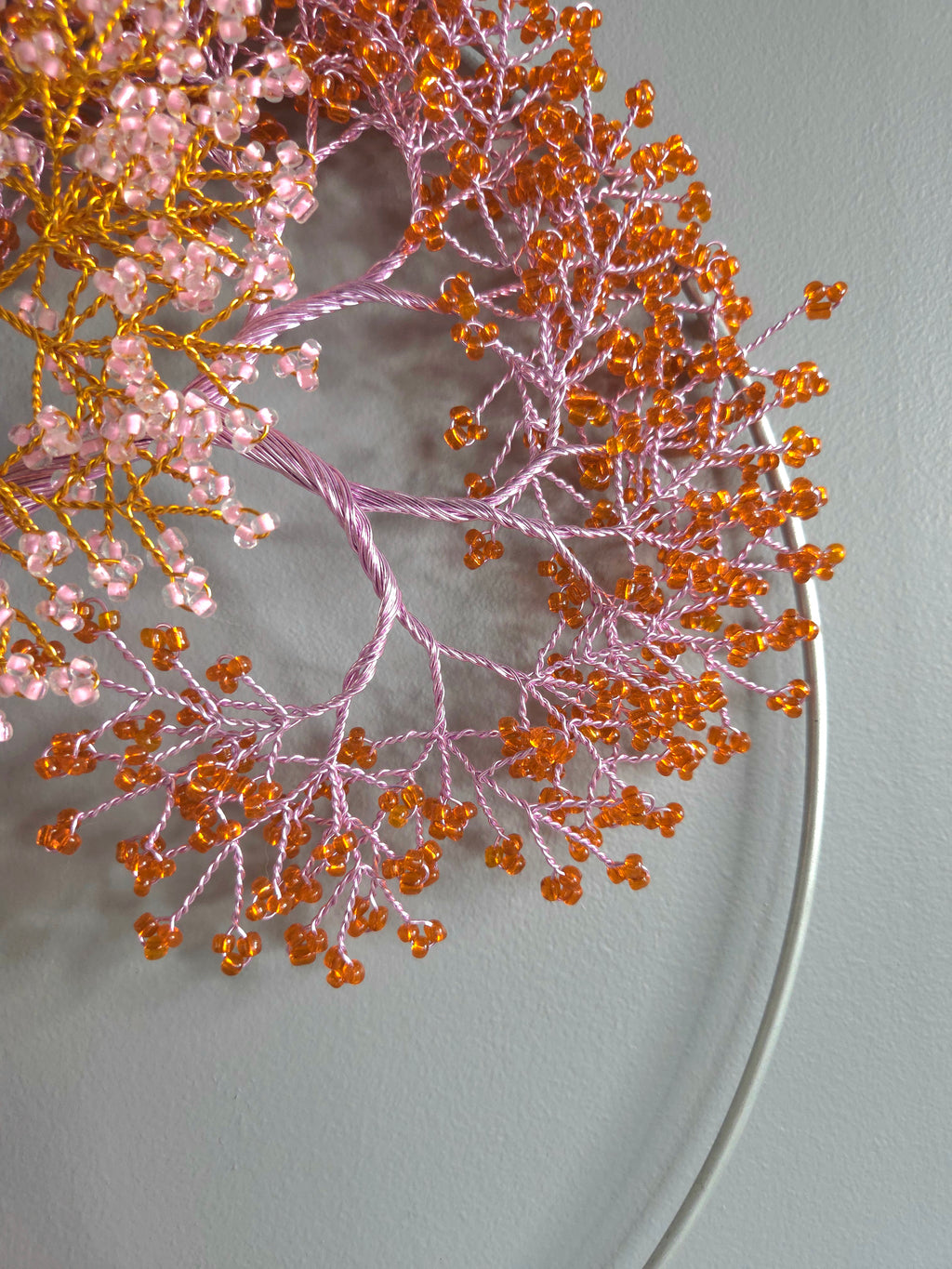 Decorative branch with pink and orange beads on a gray background