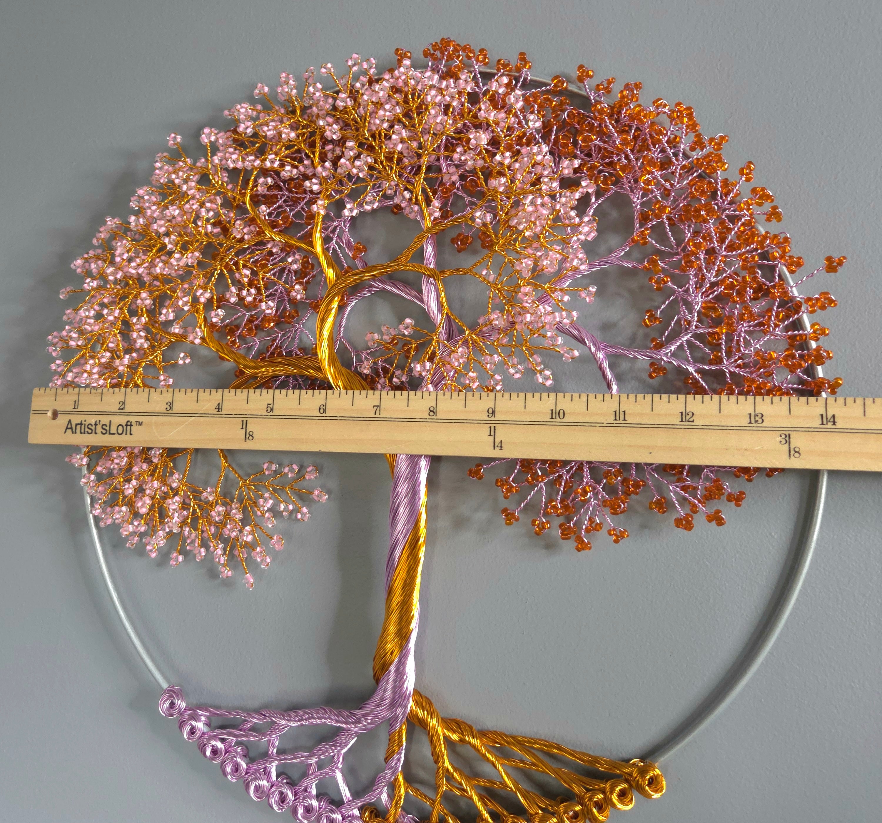 Decorative wall art of a tree with pink and gold branches, accompanied by a ruler for scale.