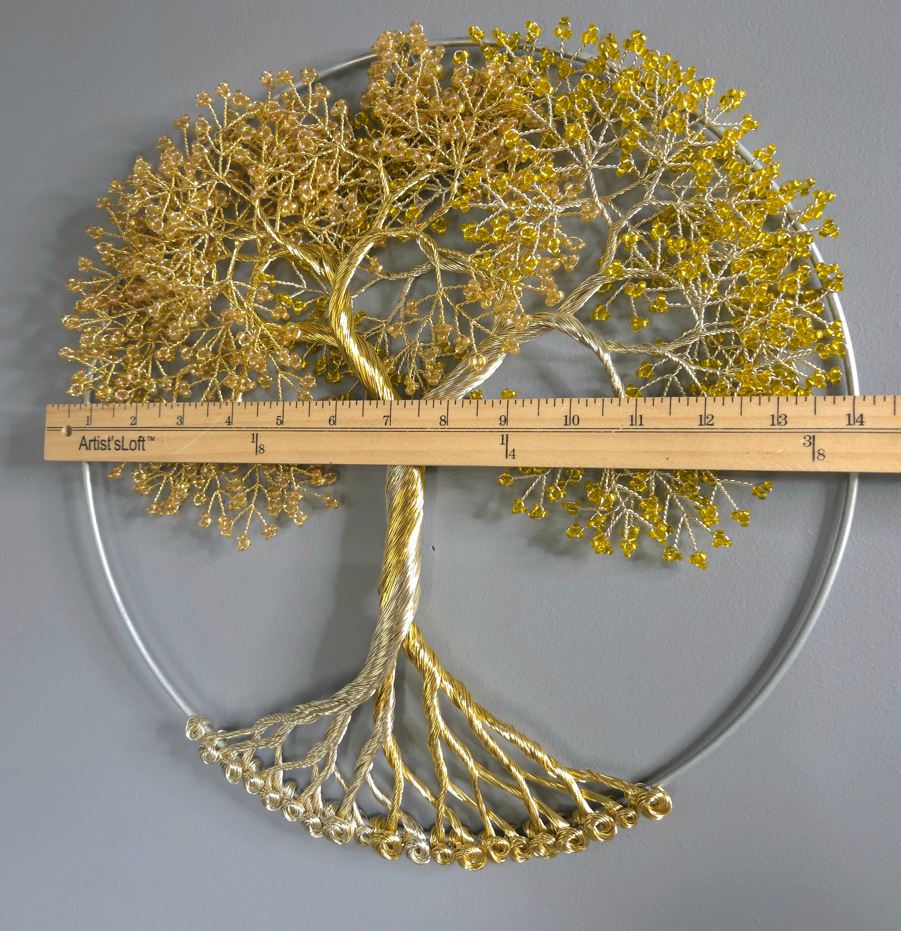 Decorative wall art of a gold tree with yellow leaves on a gray background