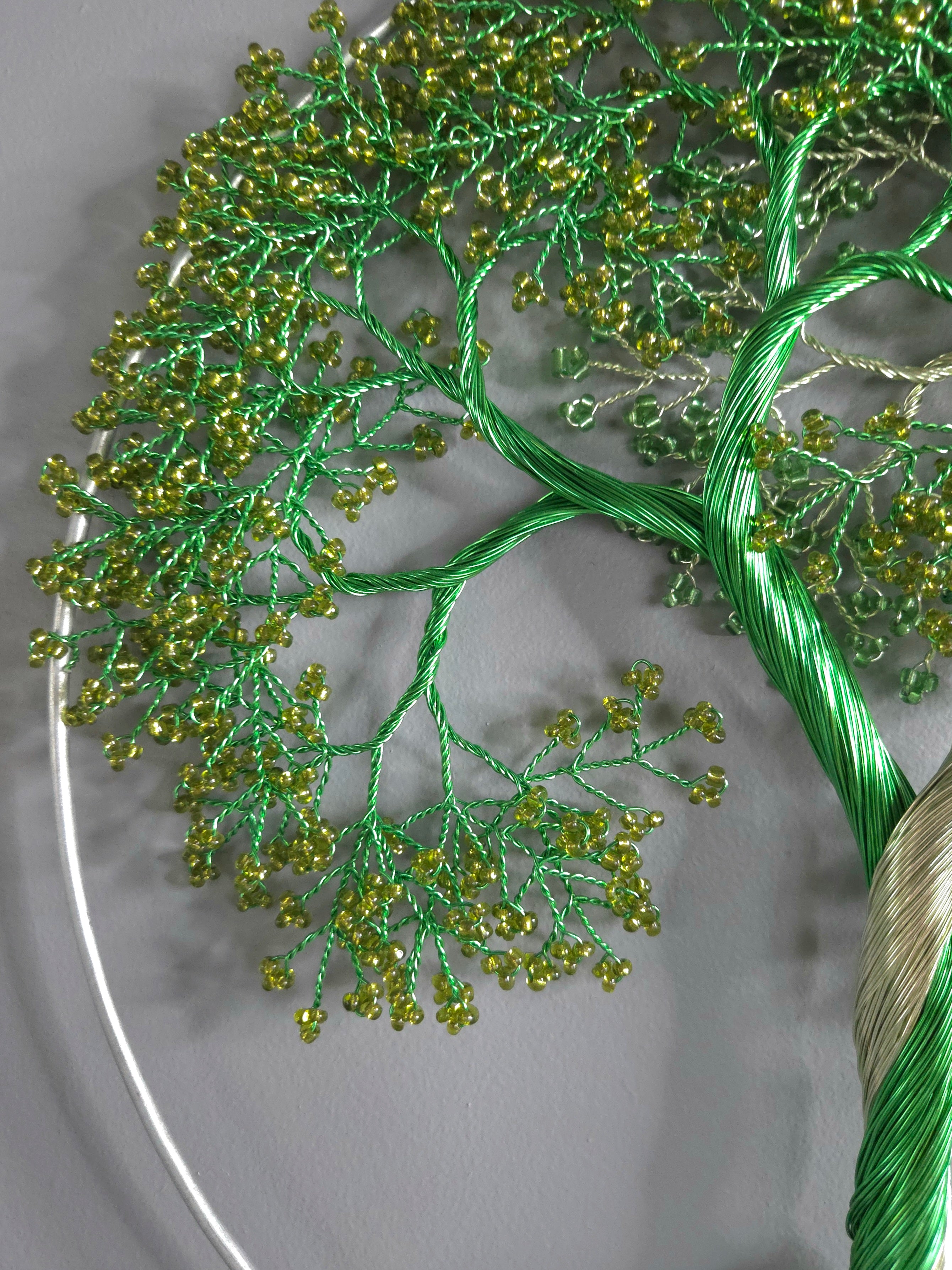Close-up of a green embroidered branch with small beads on a white background