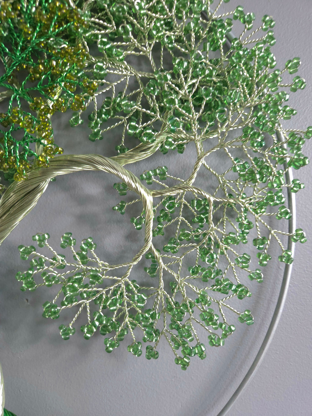 Close-up of a beaded green tree design on fabric.