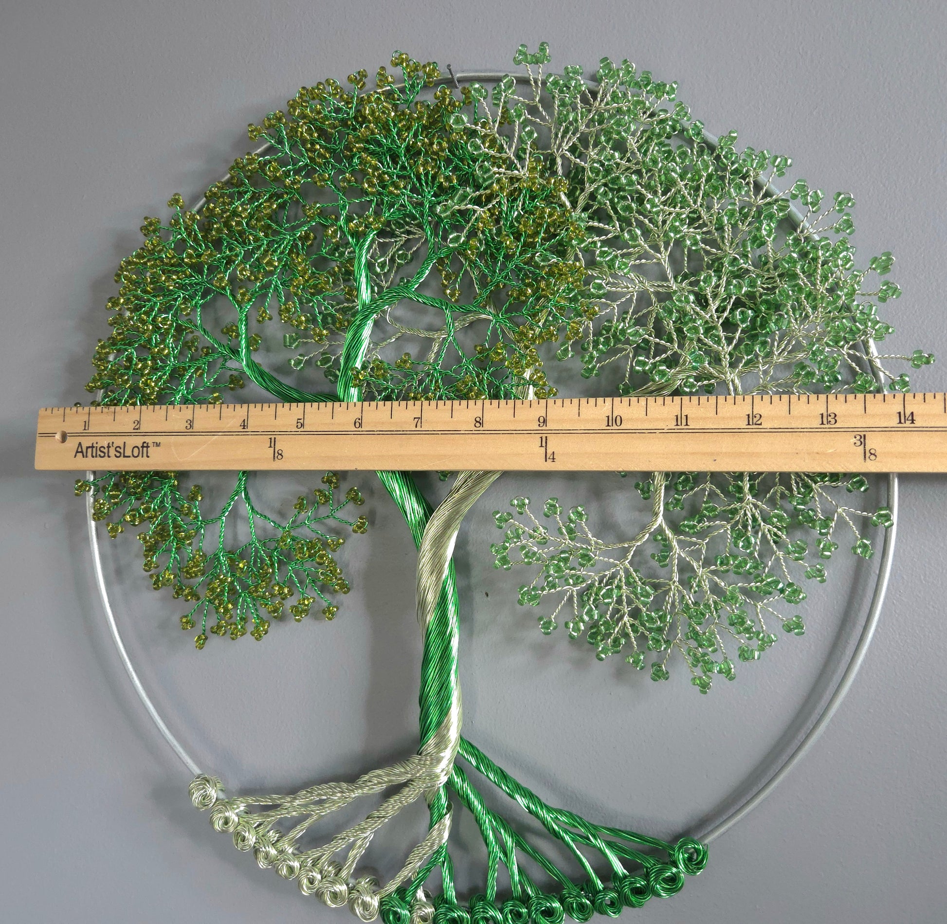Decorative green tree wall art with a ruler for scale on a gray background