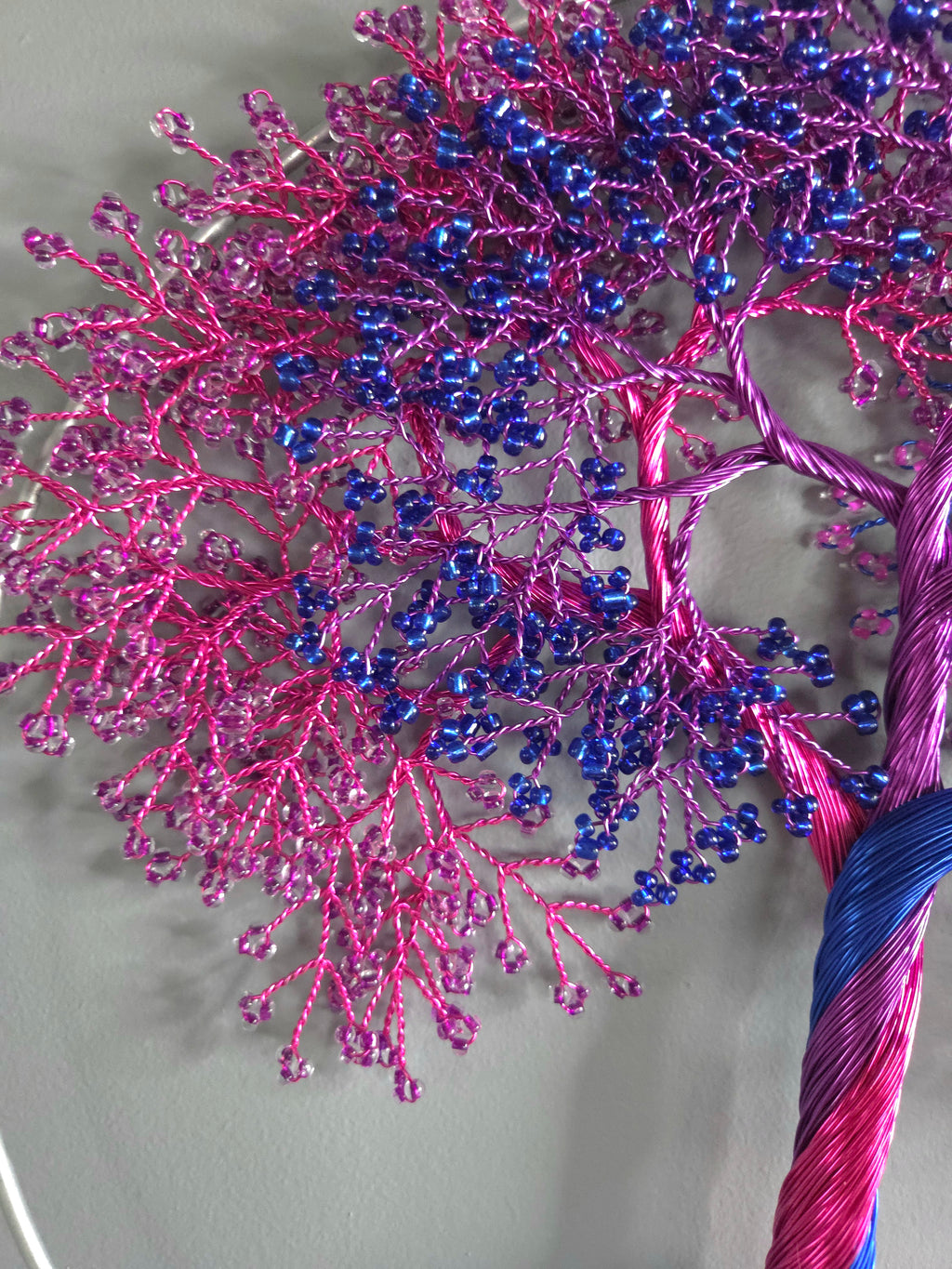 Decorative wall art of a tree with pink and blue branches on a light gray background