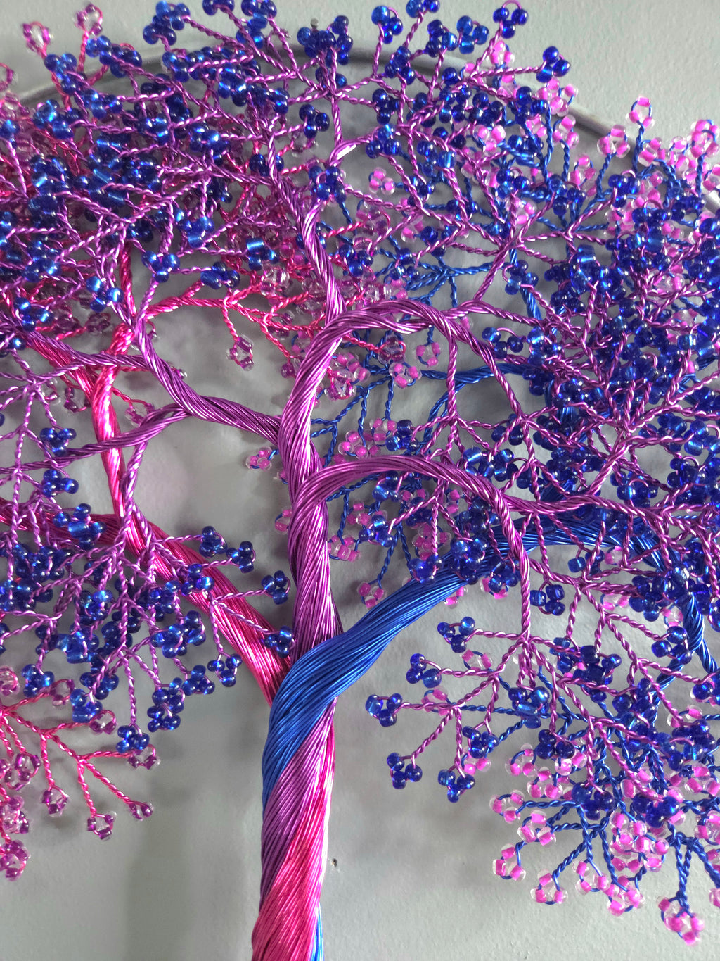 Decorative wall art of a tree with pink and blue branches on a light gray background