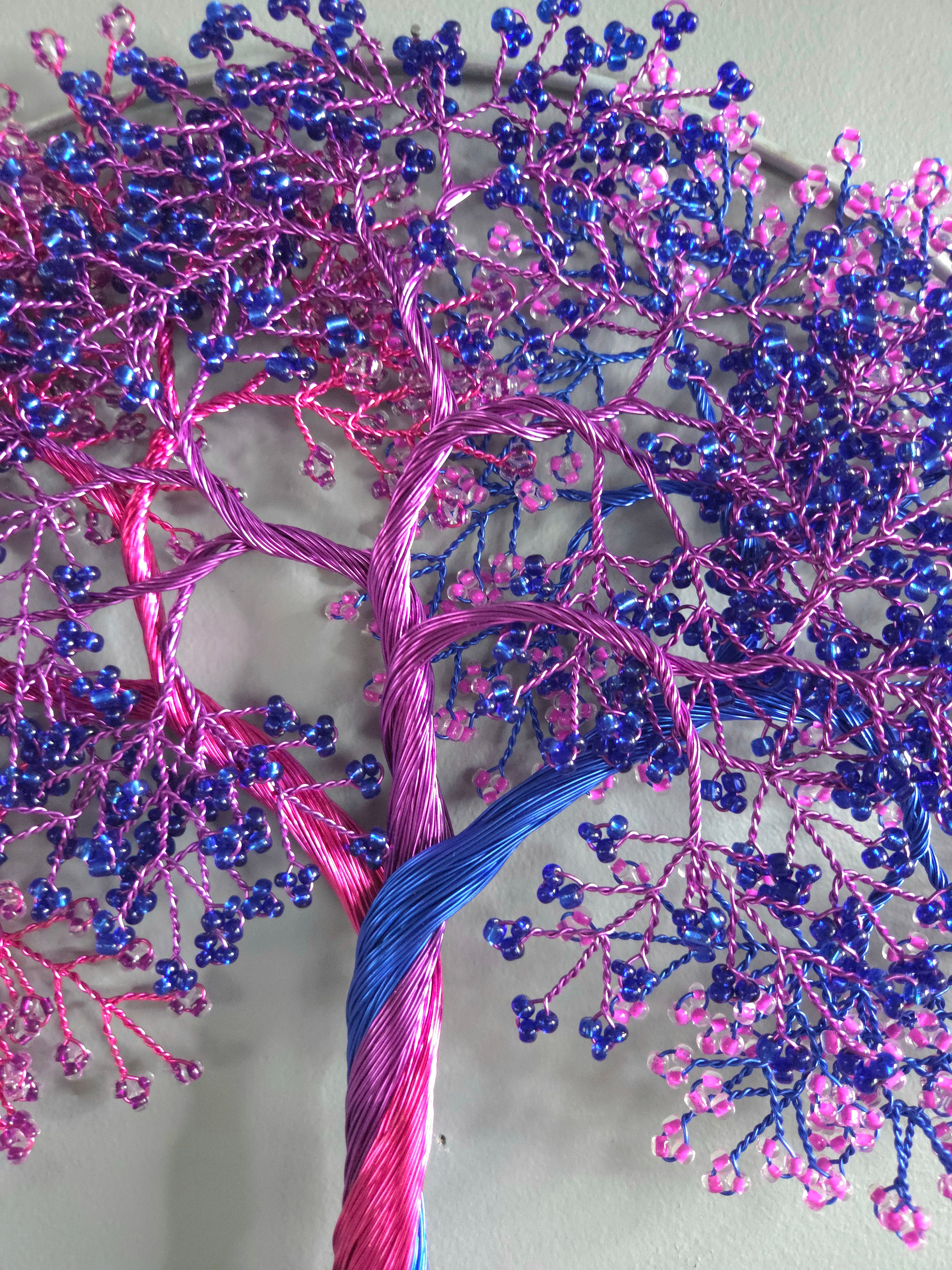 Decorative wall art of a tree with pink and blue branches on a light gray background