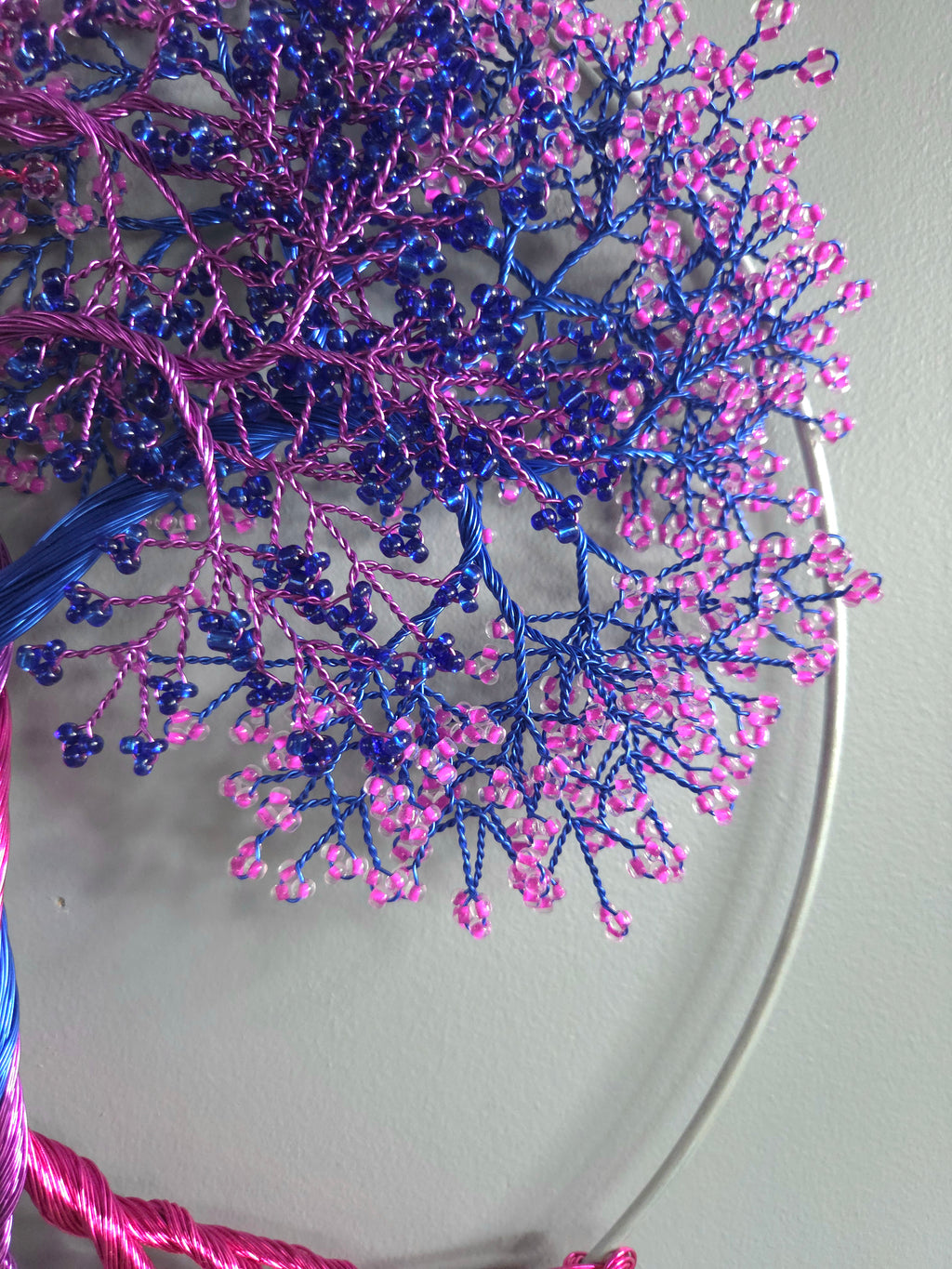 Decorative wall art of a tree with pink and blue branches on a light gray background