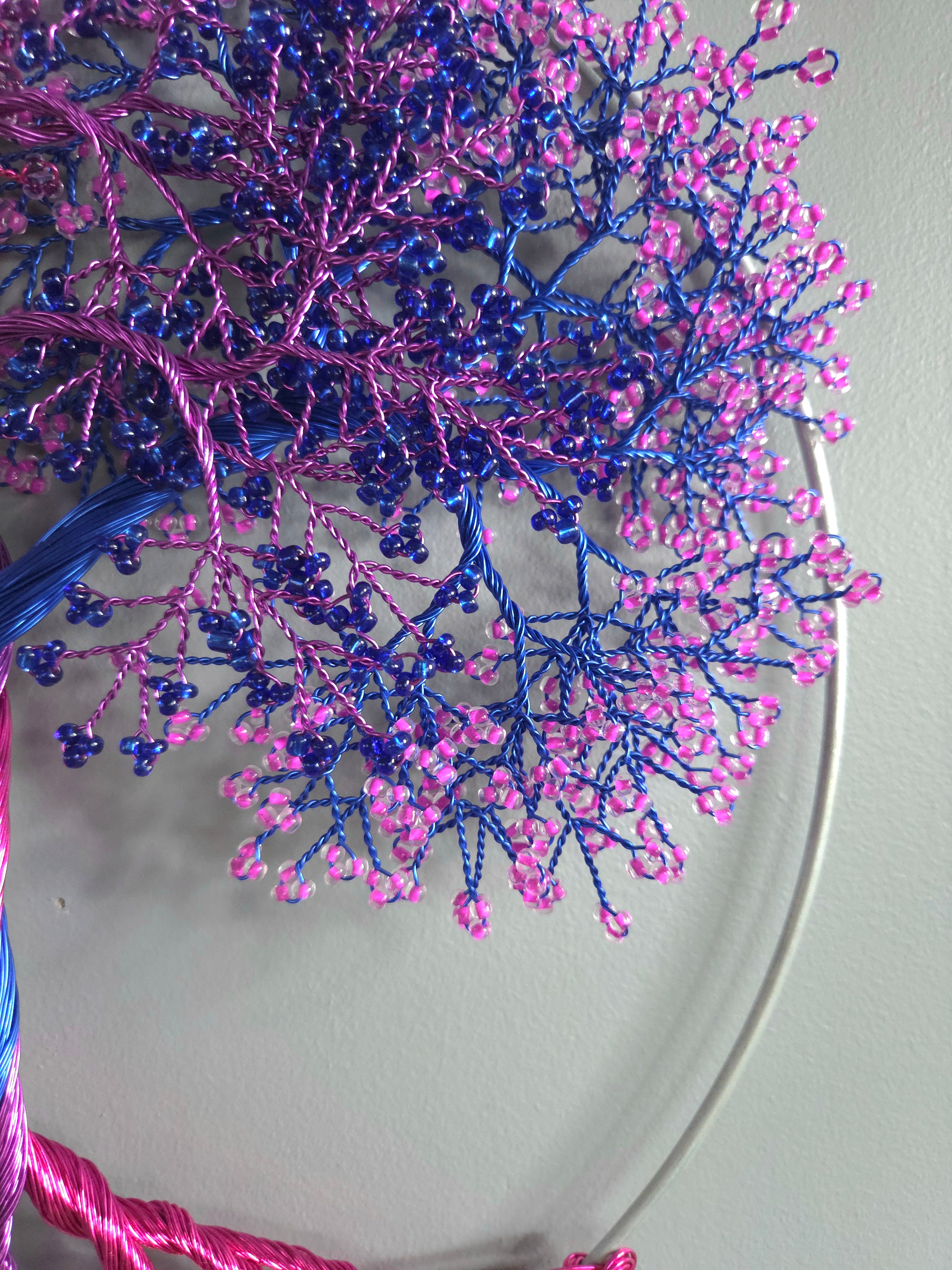 Decorative wall art of a tree with pink and blue branches on a light gray background