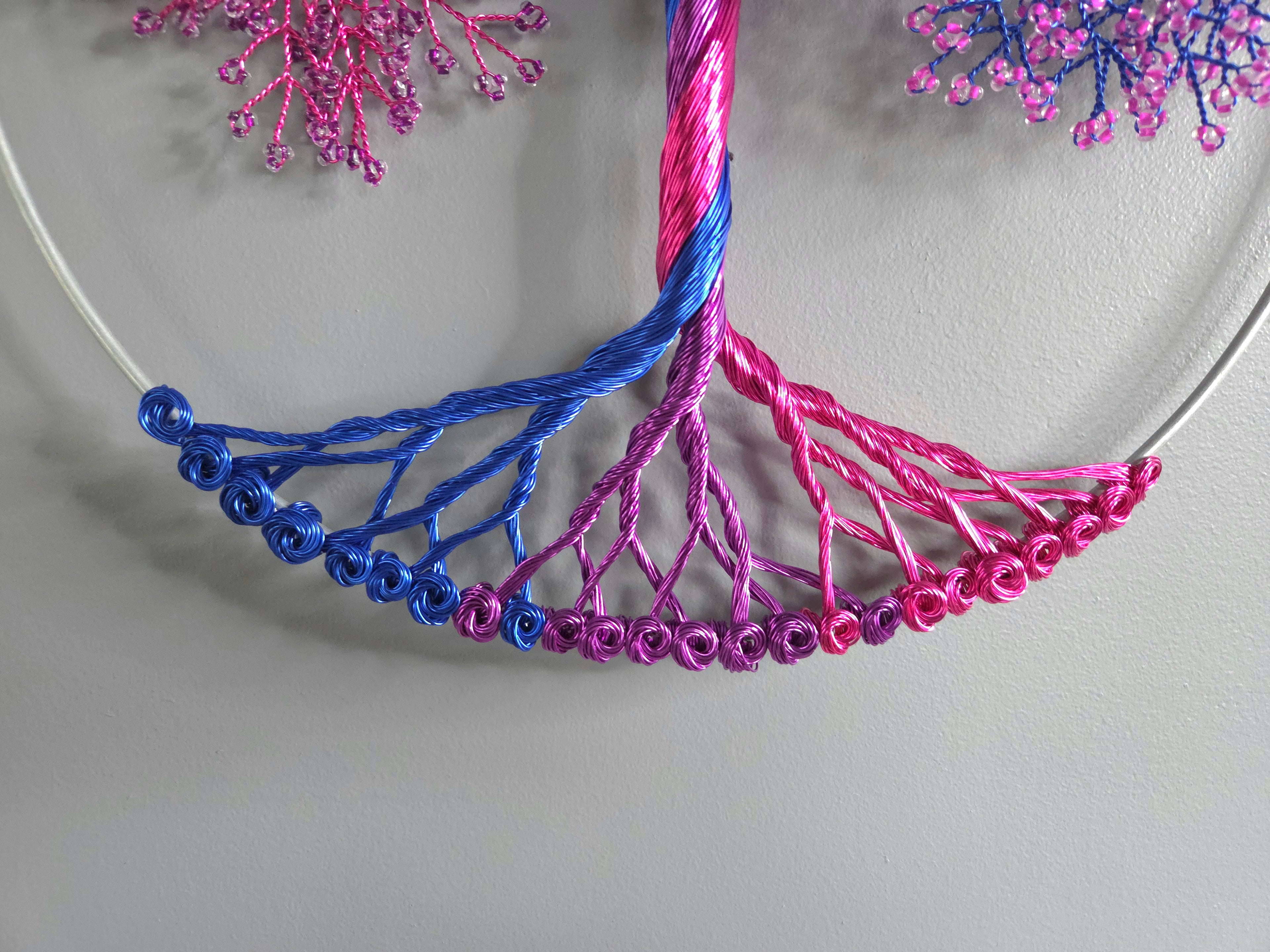 Decorative wall art of a tree with pink and blue branches on a light gray background