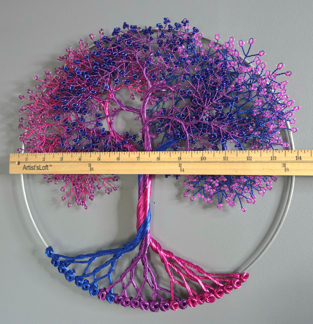 Decorative wall art of a tree with pink and blue branches on a light gray background