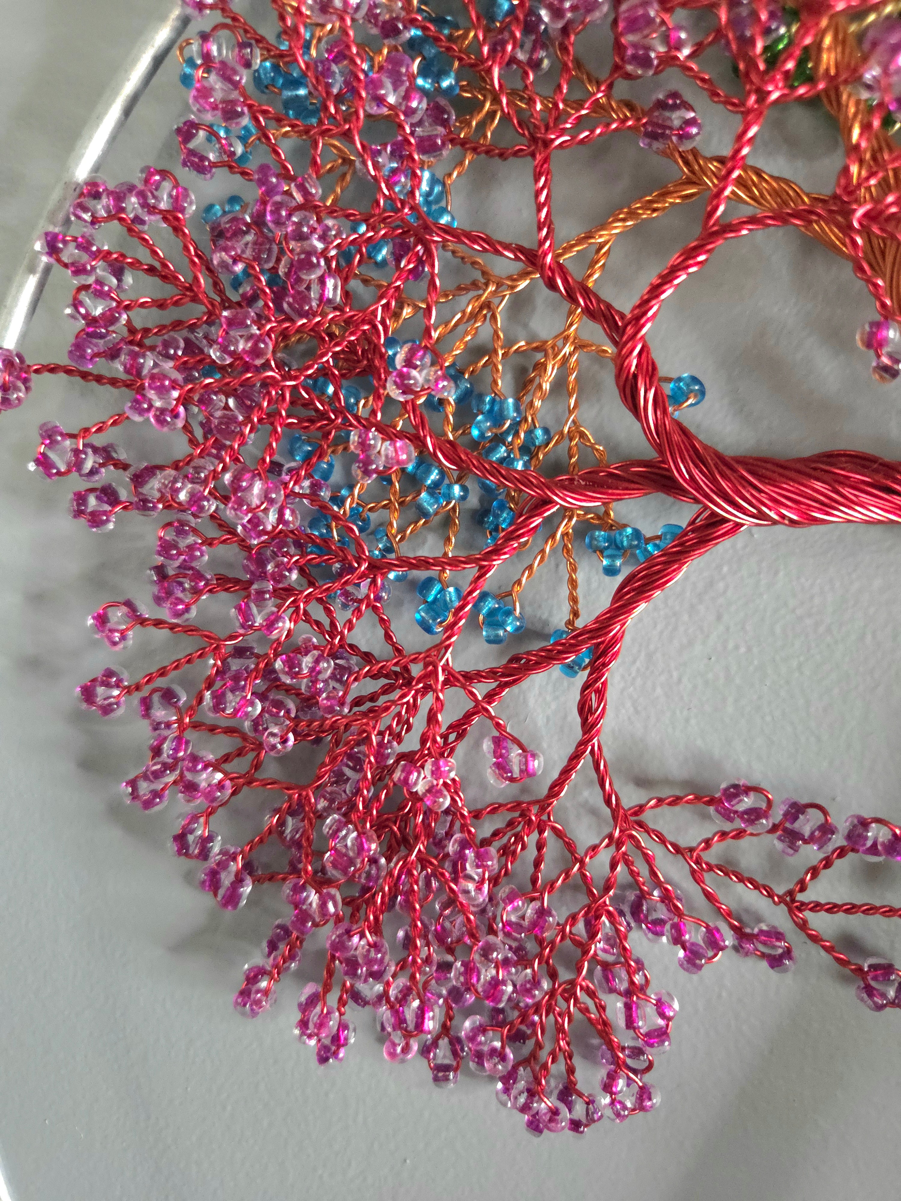 Close-up of a beaded tree branch with pink and blue beads on a white background