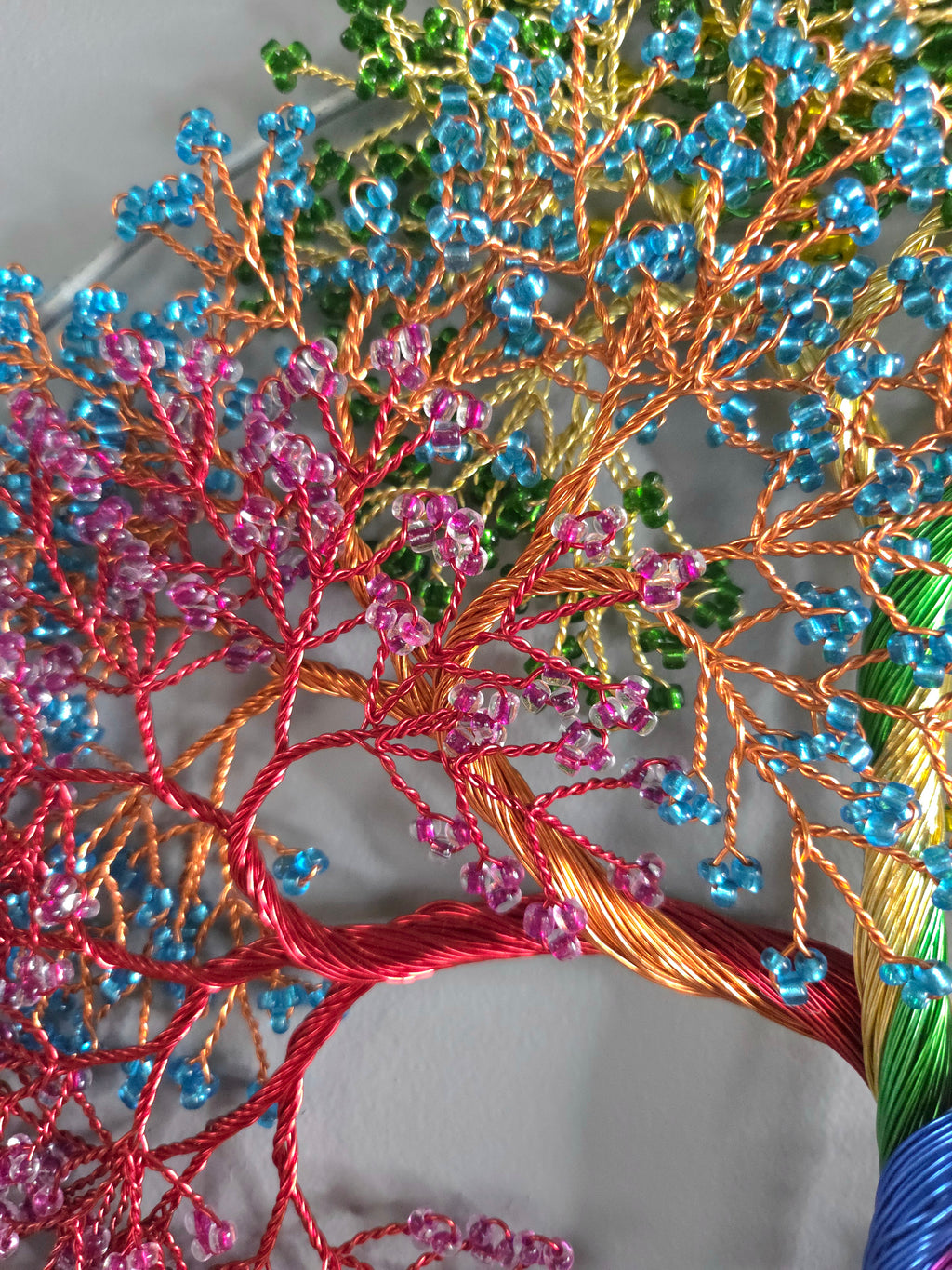 Close-up of a beaded tree sculpture with multicolored beads on a white background