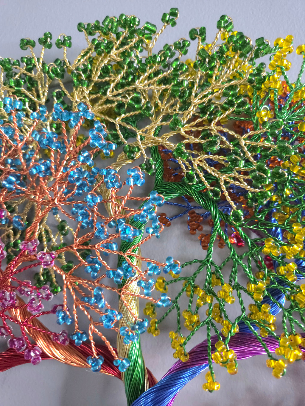 Close-up of colorful beaded and embroidered floral design on fabric.