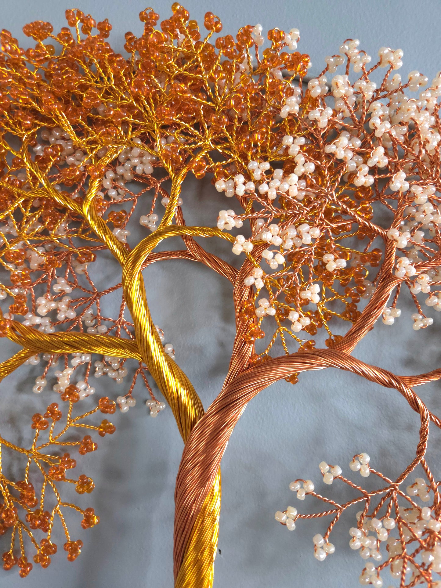 Decorative wire tree with copper and gold branches and white berries on a gray background