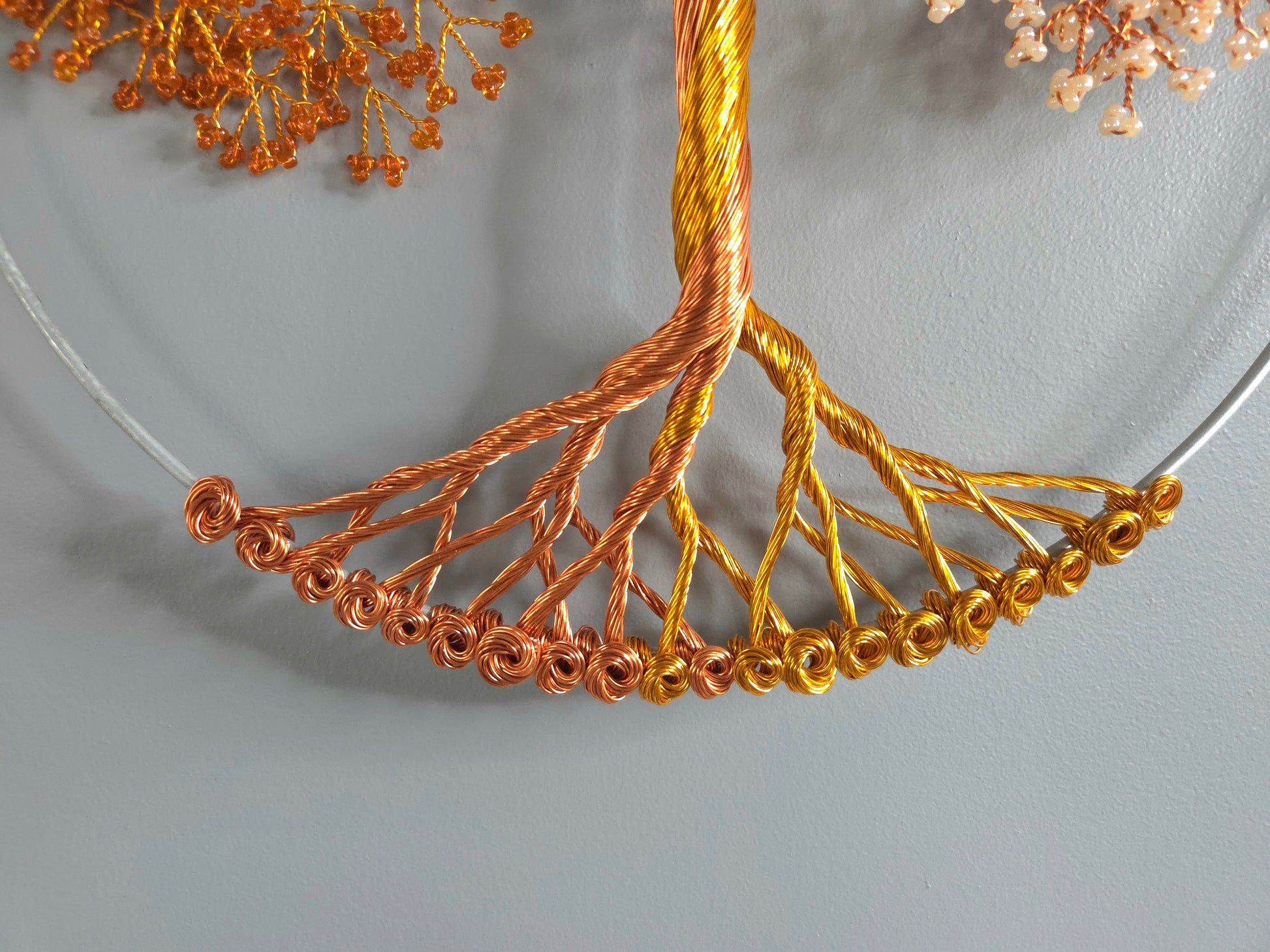 Necklace with gold and copper wire design on a gray background