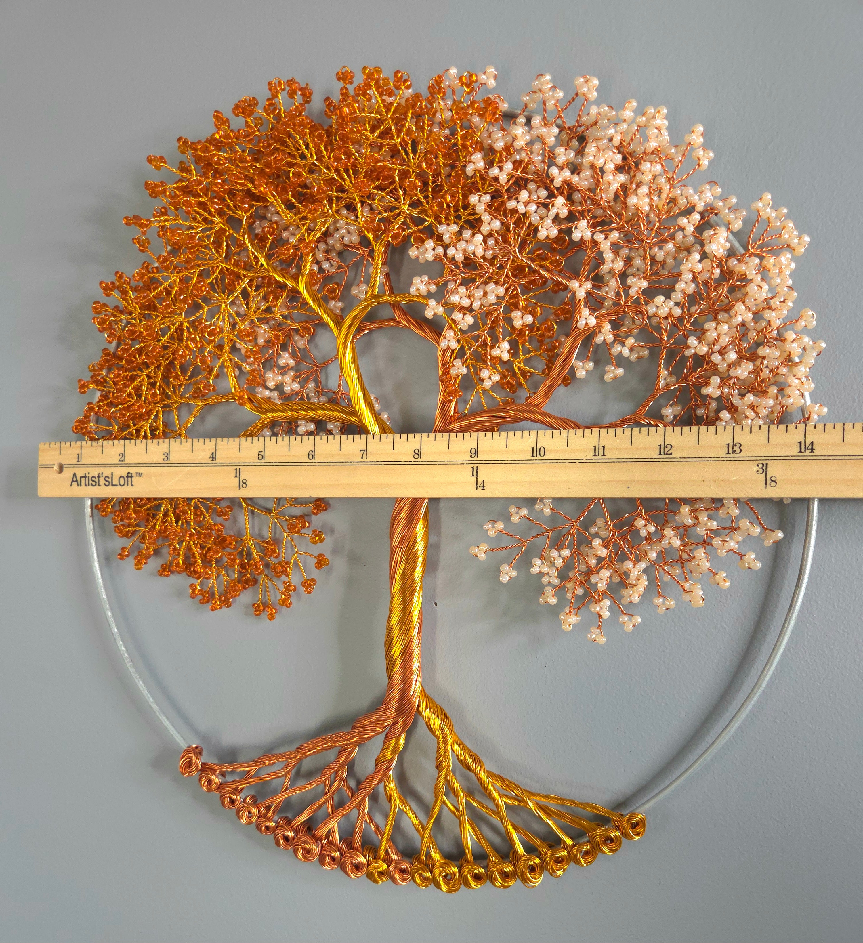 Decorative metal tree sculpture with a ruler for scale on a gray background