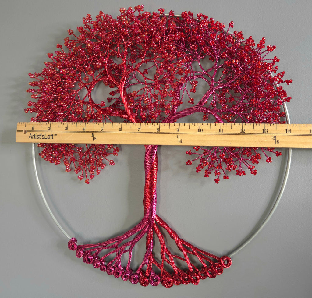 Decorative red tree sculpture with a ruler for scale on a gray background