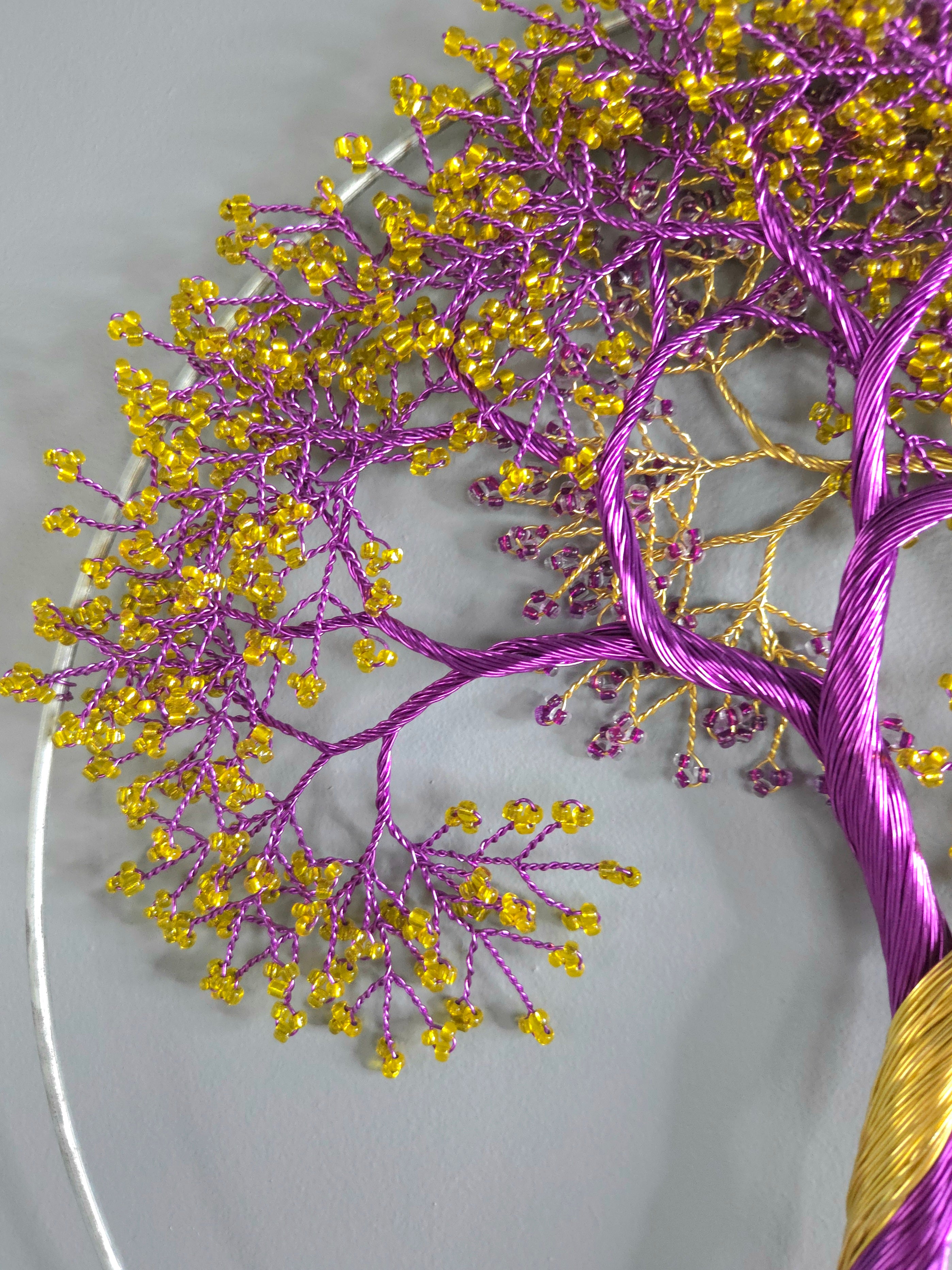 Decorative tree made of purple and gold threads on a gray background