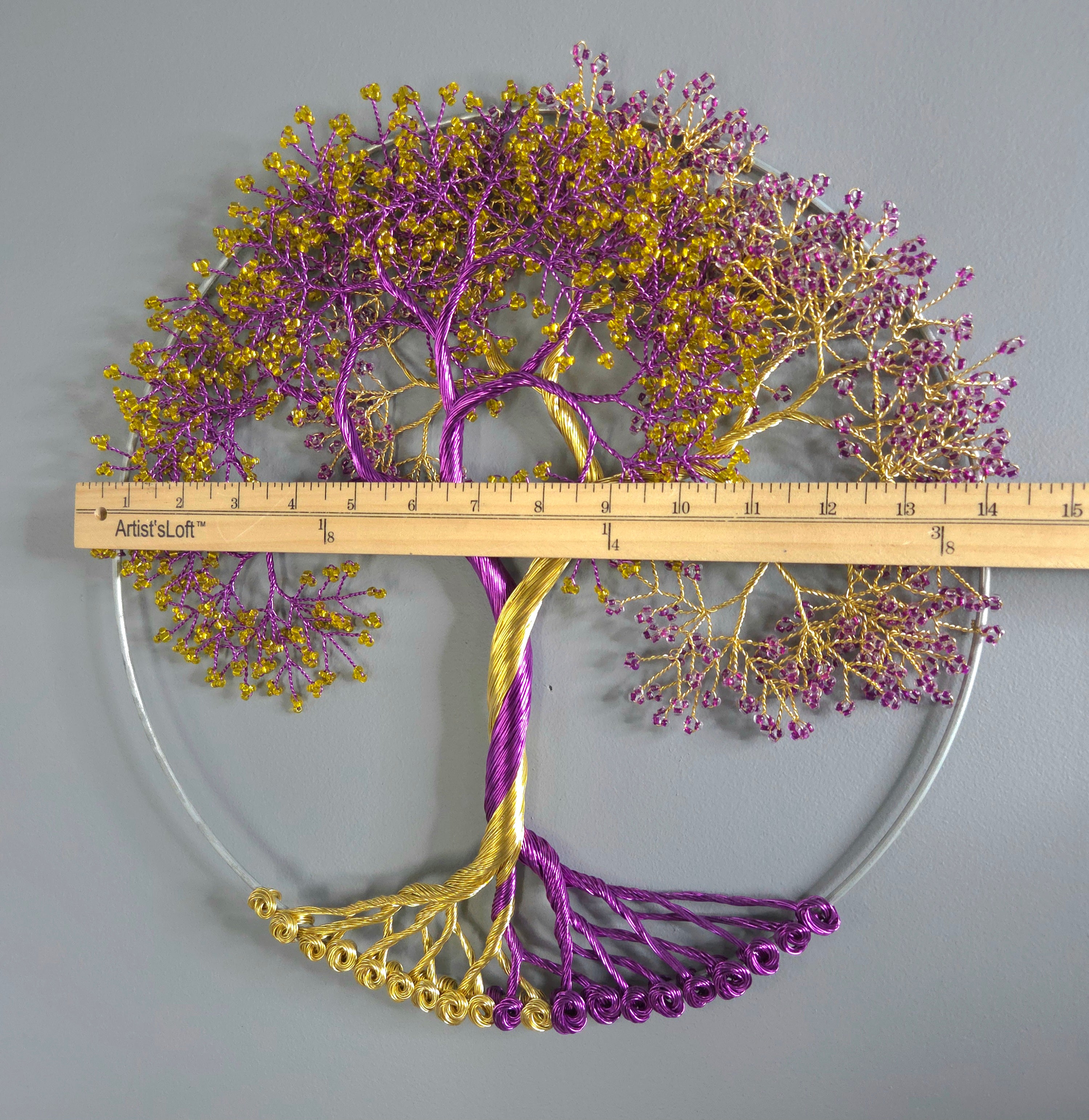 Decorative metal tree sculpture with purple and gold branches, measured against a ruler on a gray background.