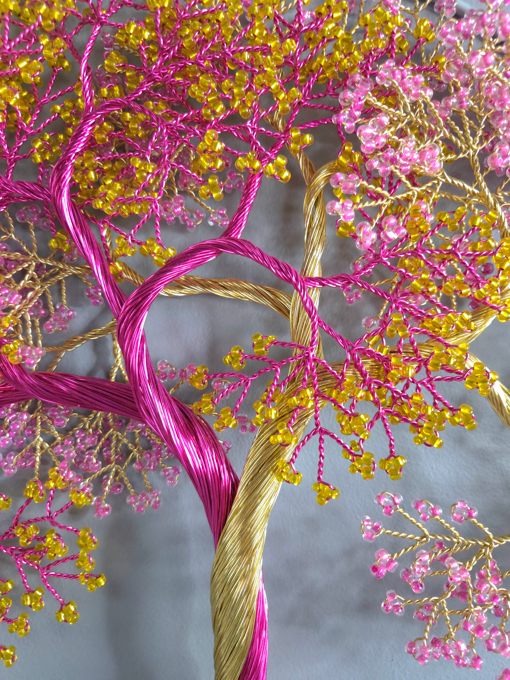 Decorative tree made of pink and gold thread on a gray background