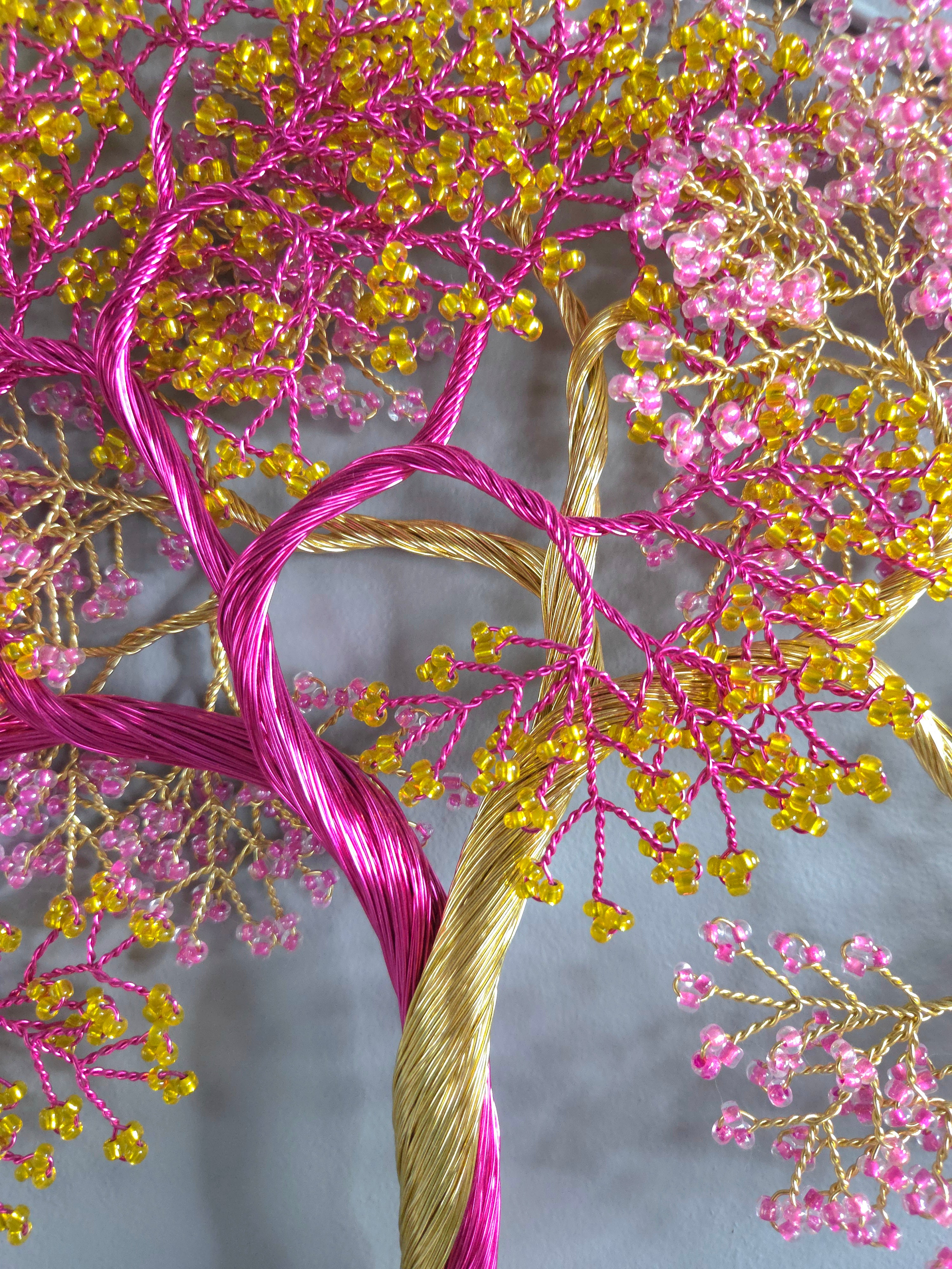 Decorative tree made of pink and gold thread on a gray background