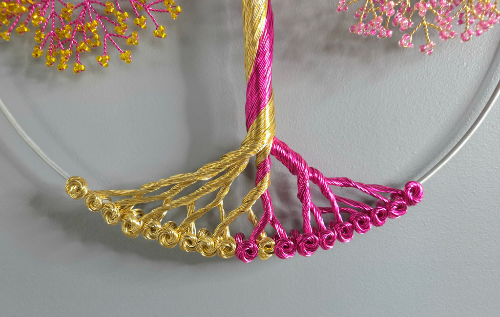 Necklace with gold and pink beaded fringe on a gray background