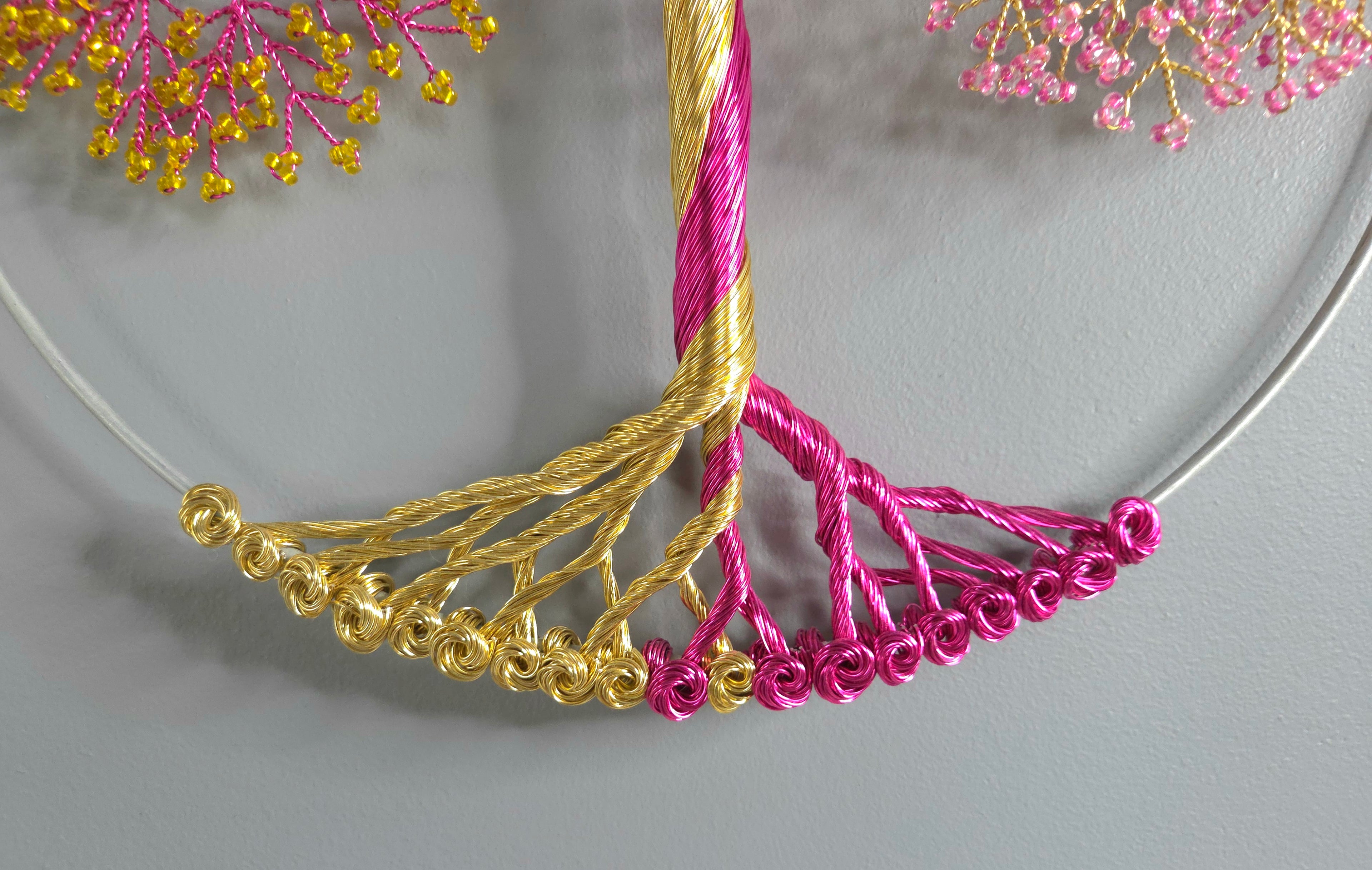 Necklace with gold and pink beaded fringe on a gray background