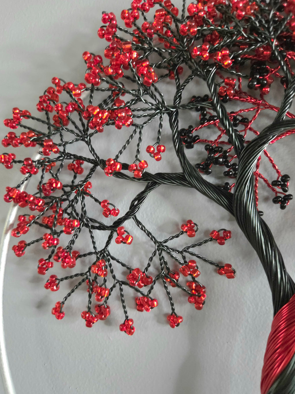 Decorative wall art of a tree with red and black branches on a gray background