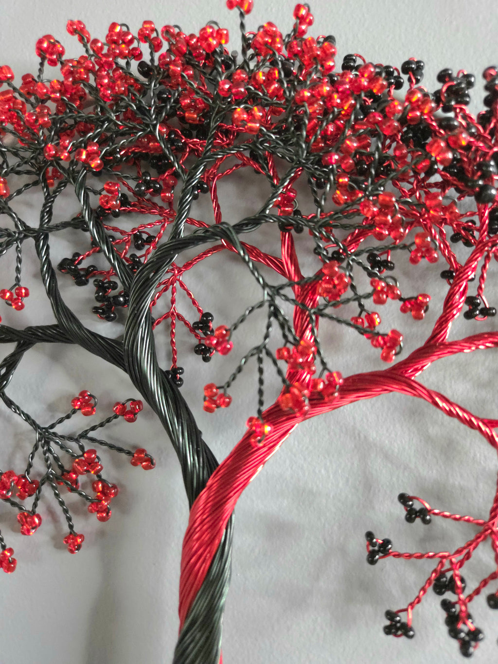 Decorative wall art of a tree with red and black branches on a gray background