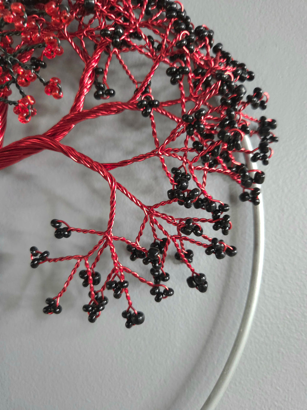 Decorative wall art of a tree with red and black branches on a gray background