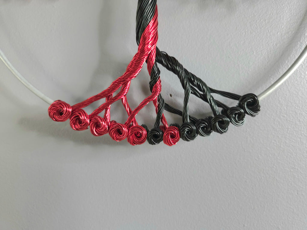 Decorative wall art of a tree with red and black branches on a gray background