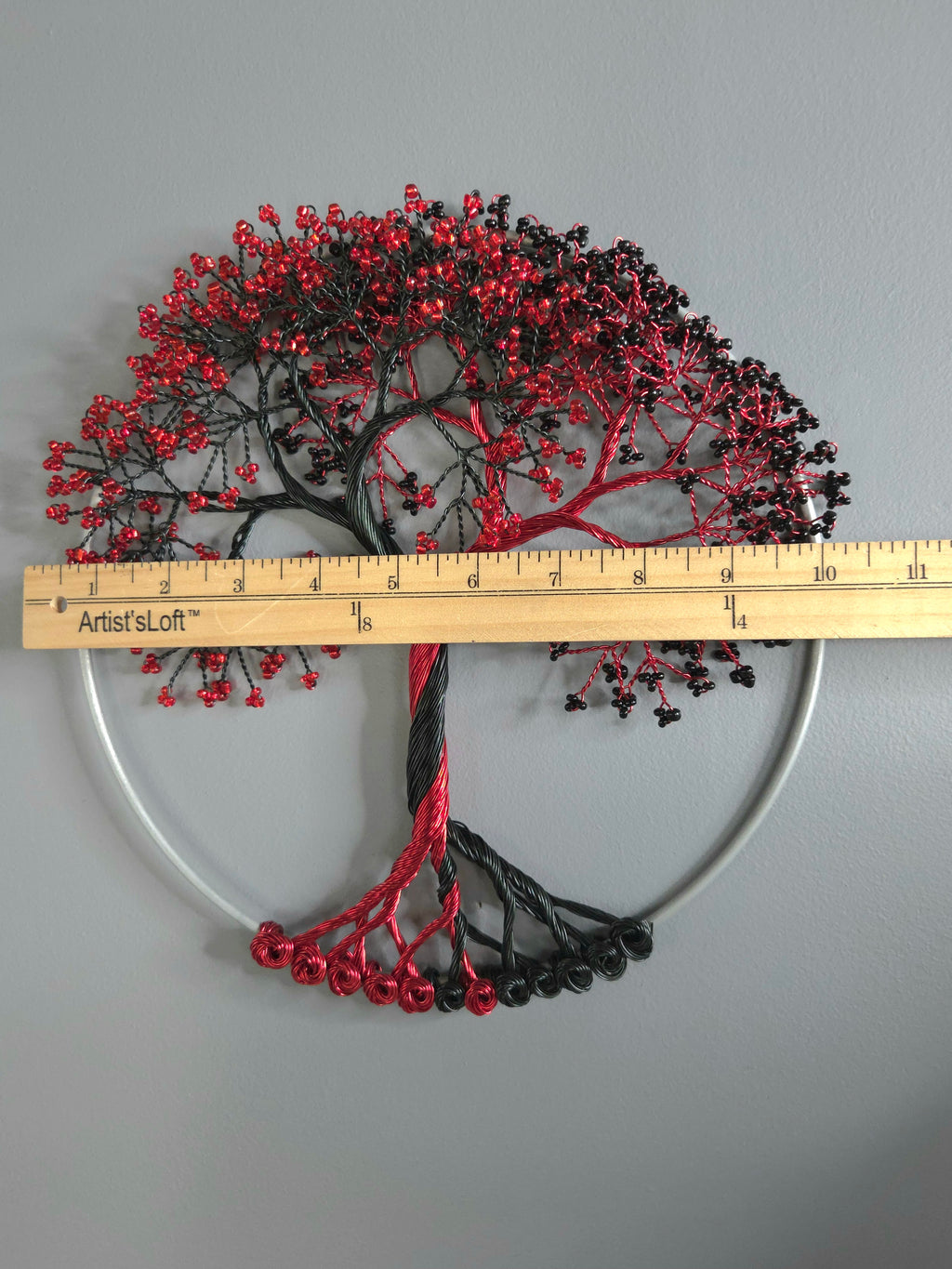 Decorative wall art of a tree with red and black branches on a gray background
