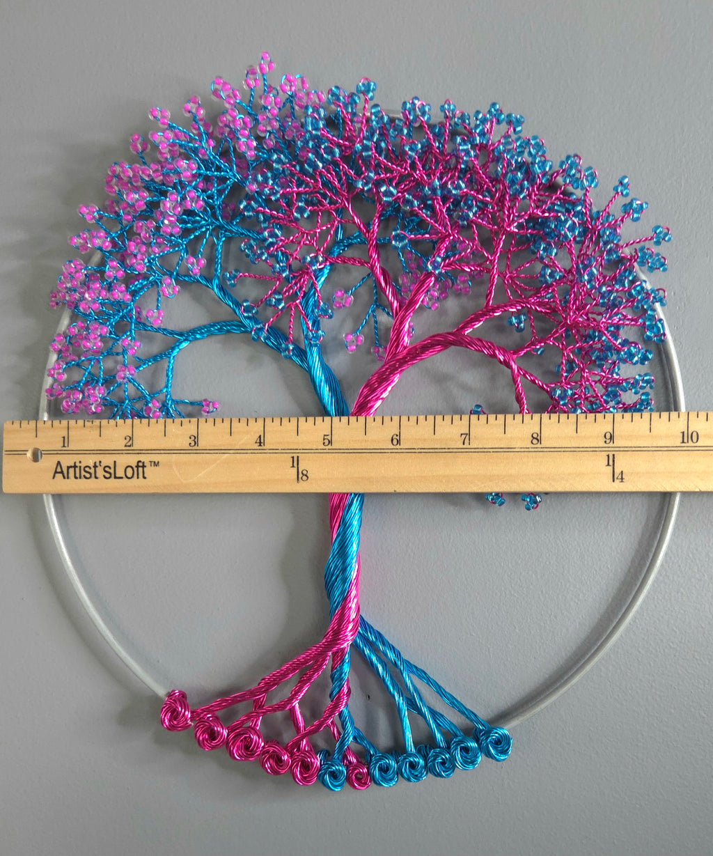 Decorative tree sculpture with pink and blue branches on a gray background, measured by a ruler.