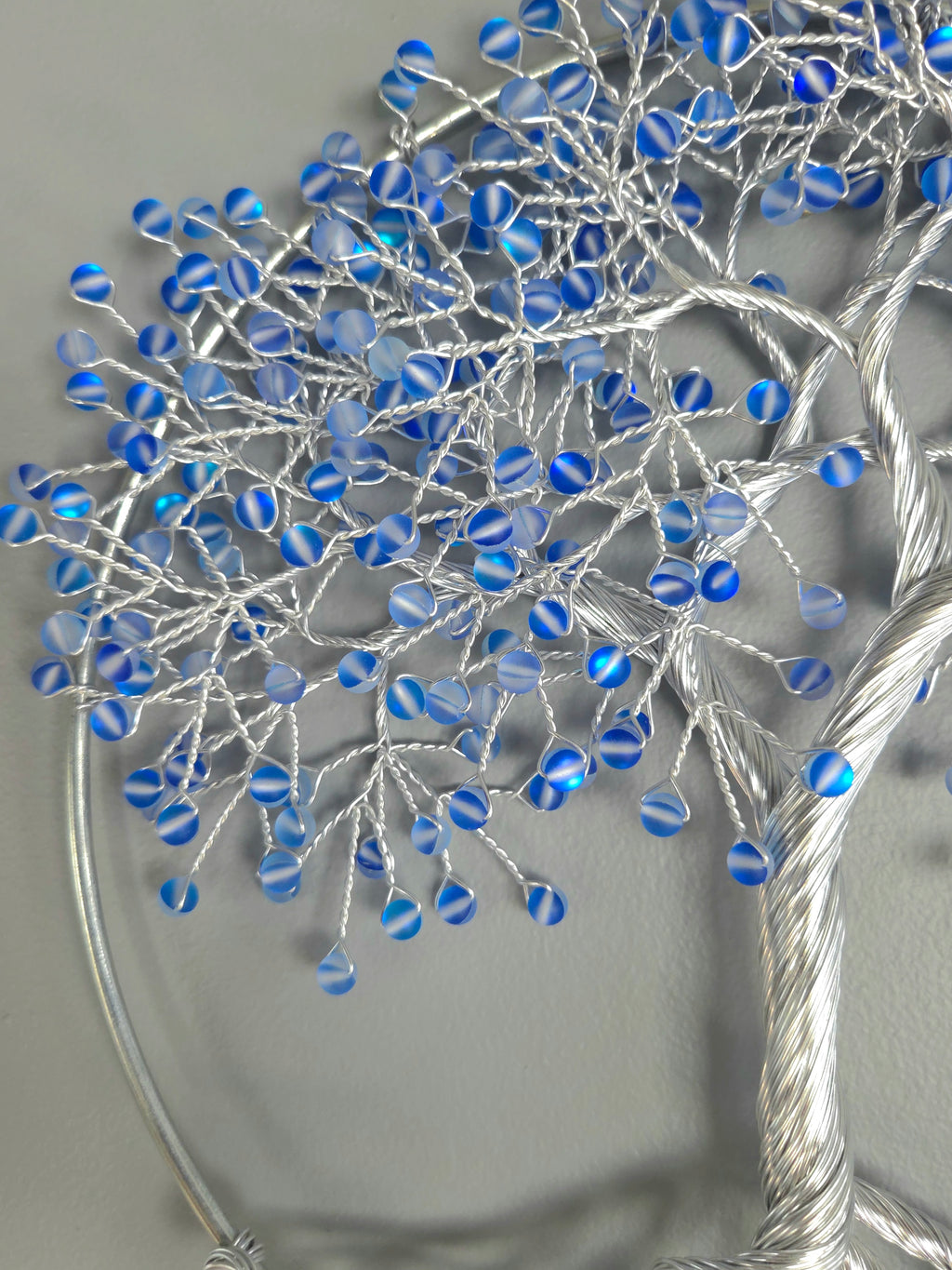 Decorative wall art of a tree with blue beads on a gray background